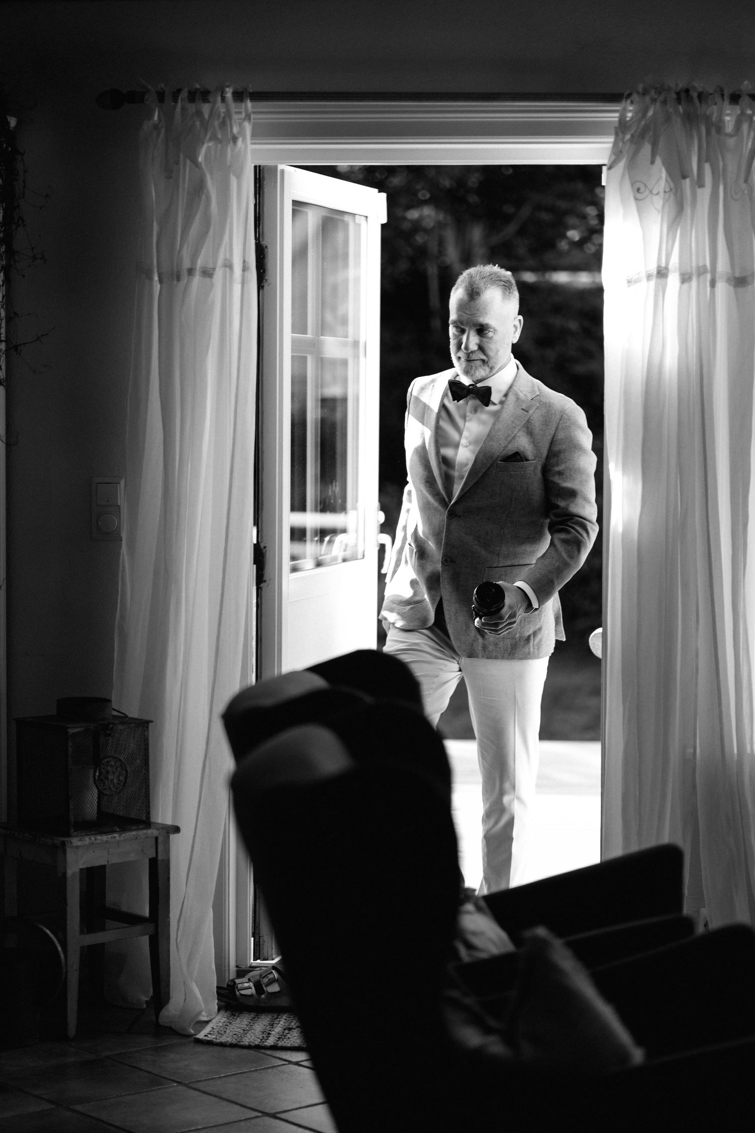 Dramatic black and white sequence showing silhouette preparing by window with natural light streaming in.