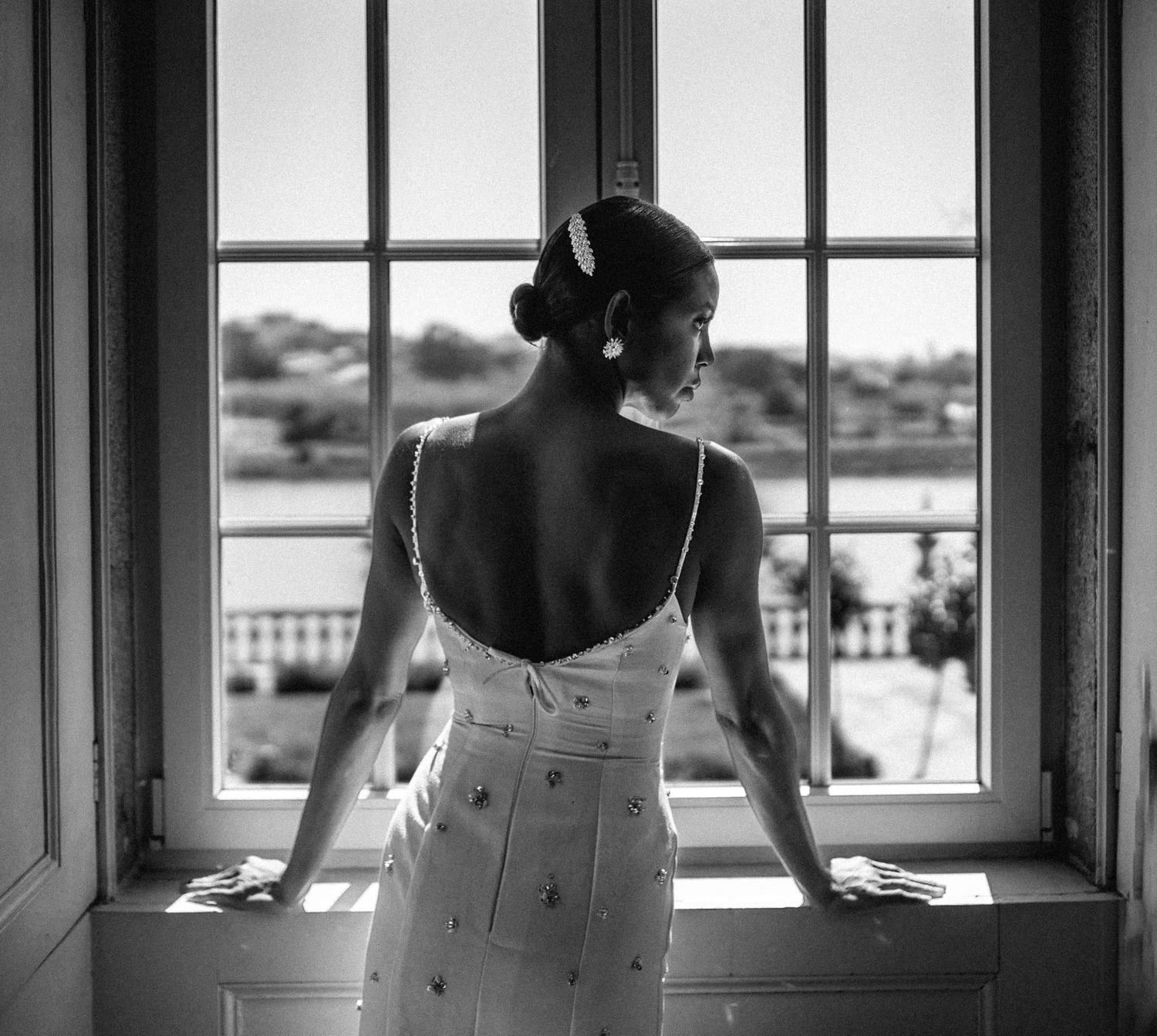 Minimalist black and white photo of a bride silhouetted against windows.