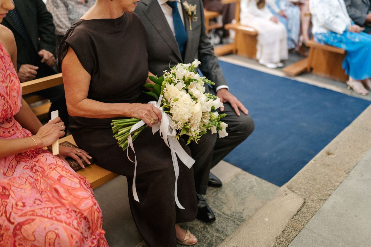 Wedding guests seated on coral-colored cushions during an elegant ceremony.