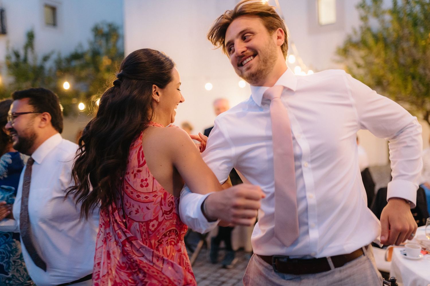 Couples dancing together at an outdoor evening wedding reception with string lights overhead.