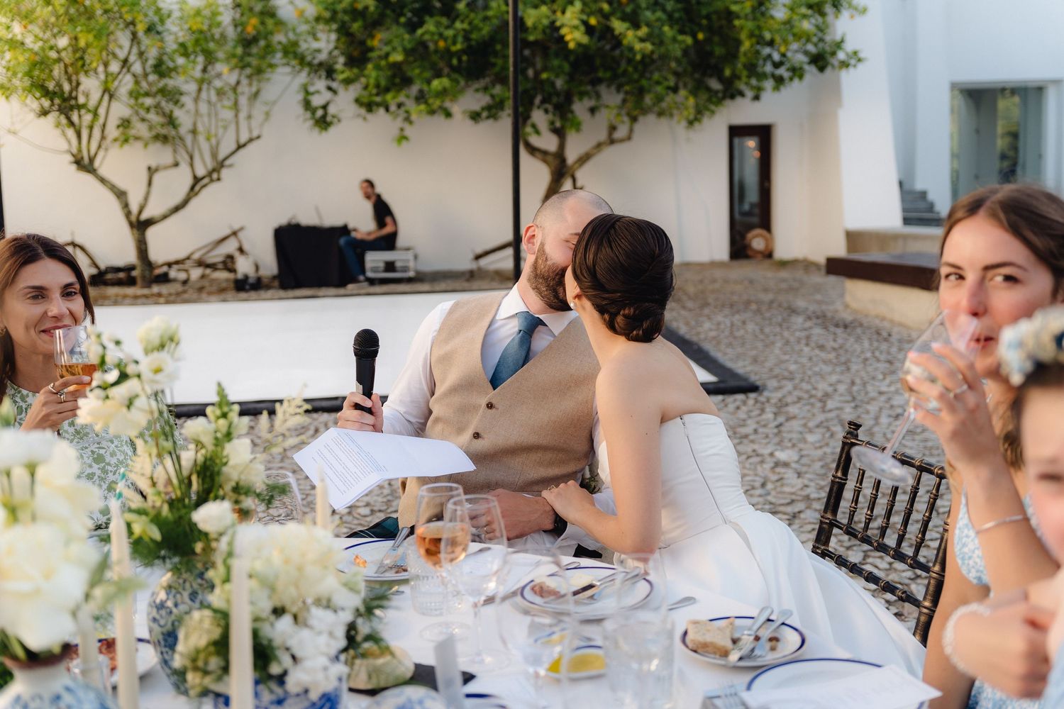 Wedding guests dining at decorated tables in a Mediterranean courtyard.