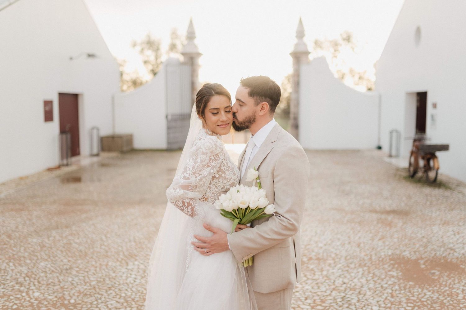 Wedding couple sharing an intimate moment in front of a white mission-style building.