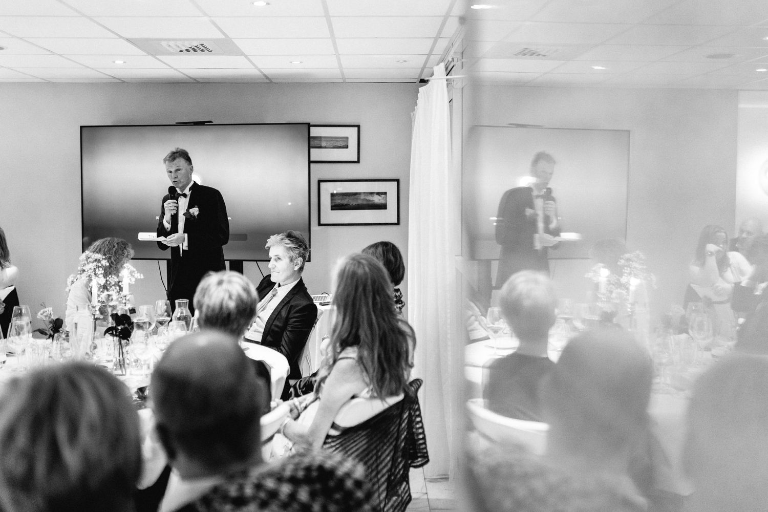 Black and white photo of wedding reception guests in a banquet hall.