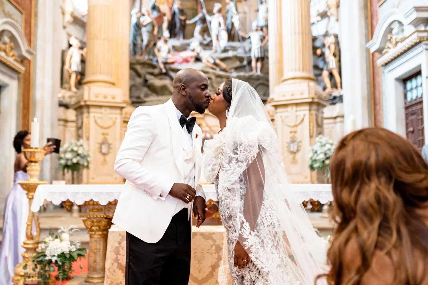 Wedding ceremony taking place in an ornate cathedral with grand columns and decorative architecture.