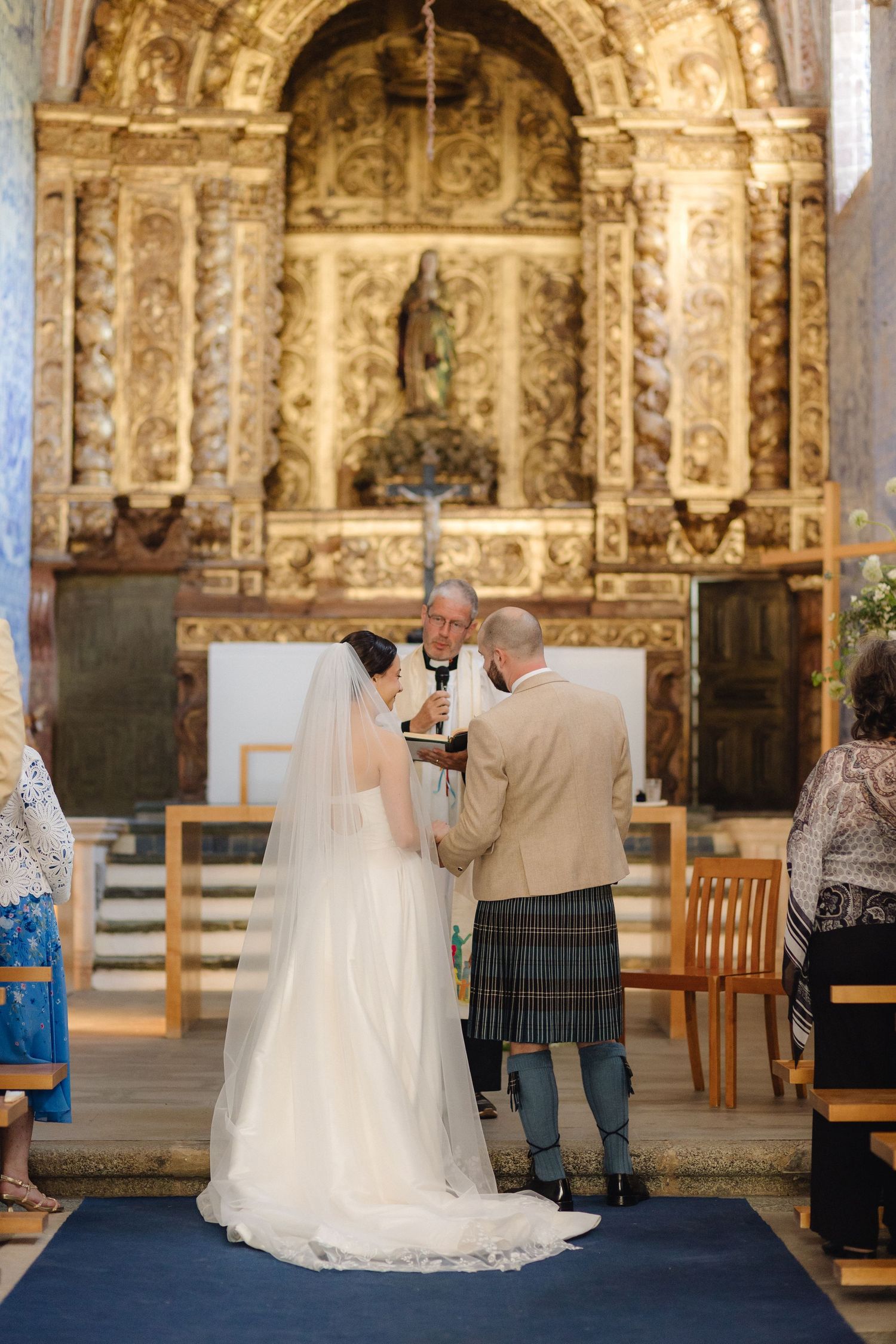 Wedding ceremony in front of an ornate golden altar with blue tile walls in a Portuguese chapel.