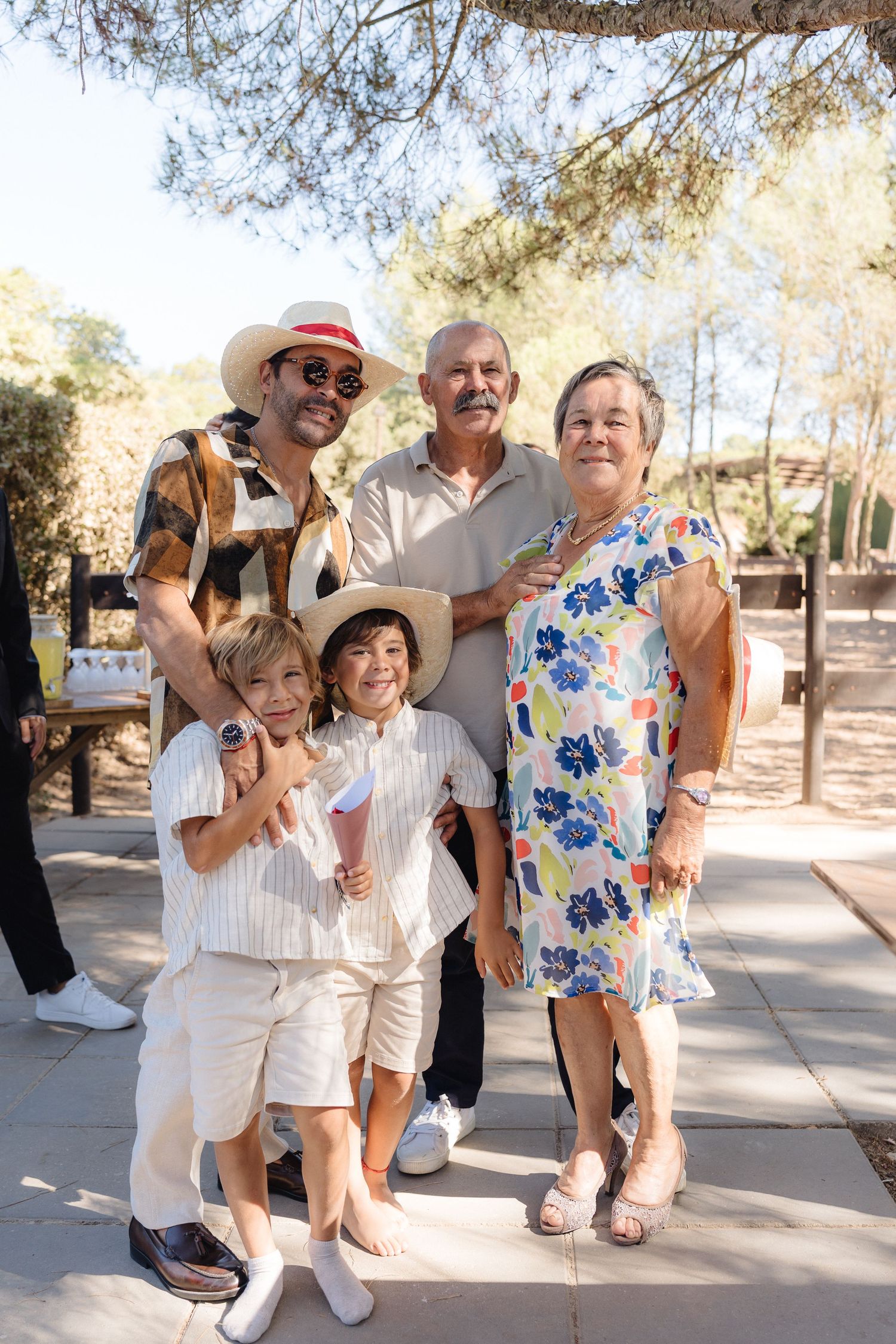 Group of wedding guests in white and floral outfits enjoying a candid moment outdoors.