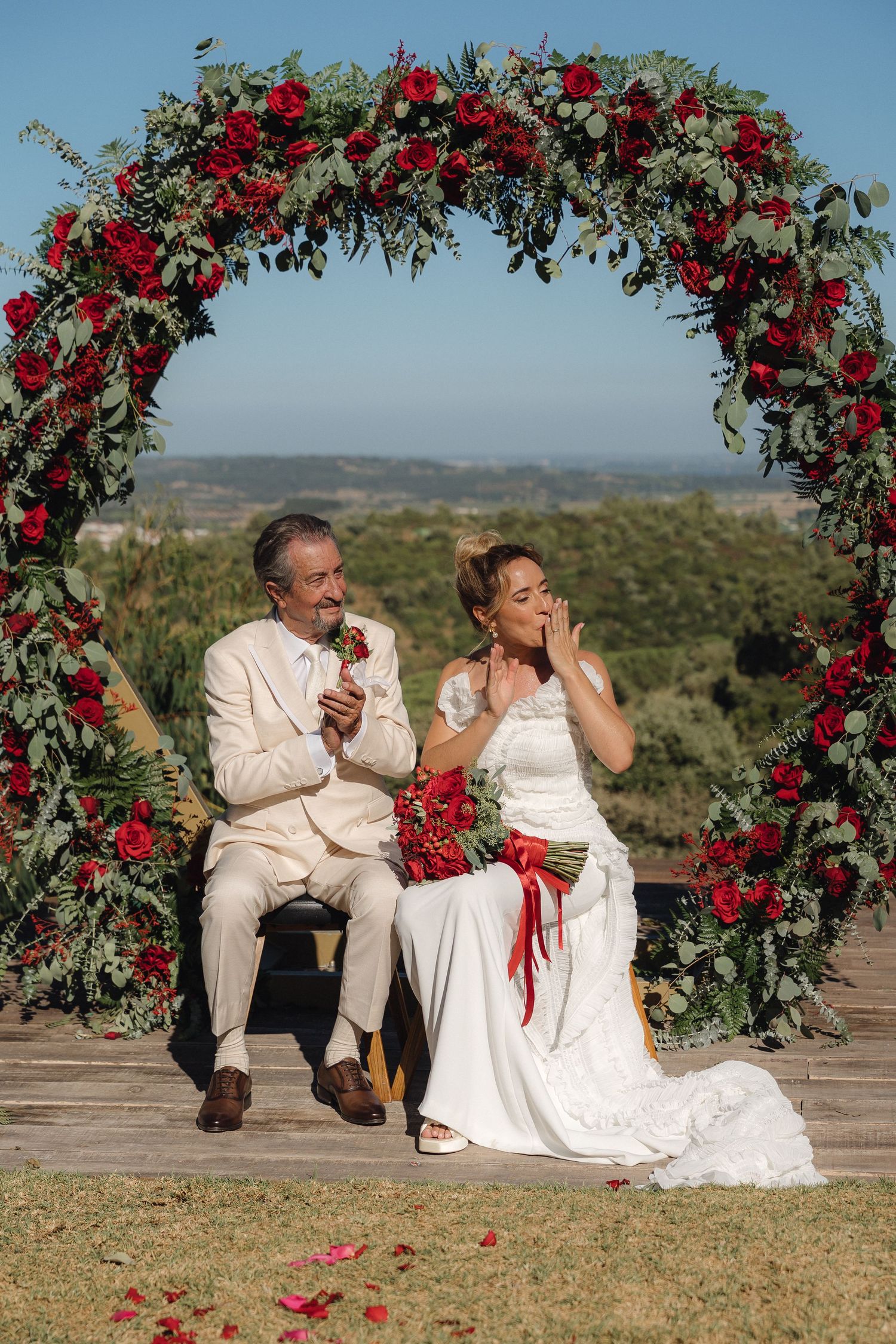 Wedding ceremony setup with red rose arch overlooking scenic mountain landscape.