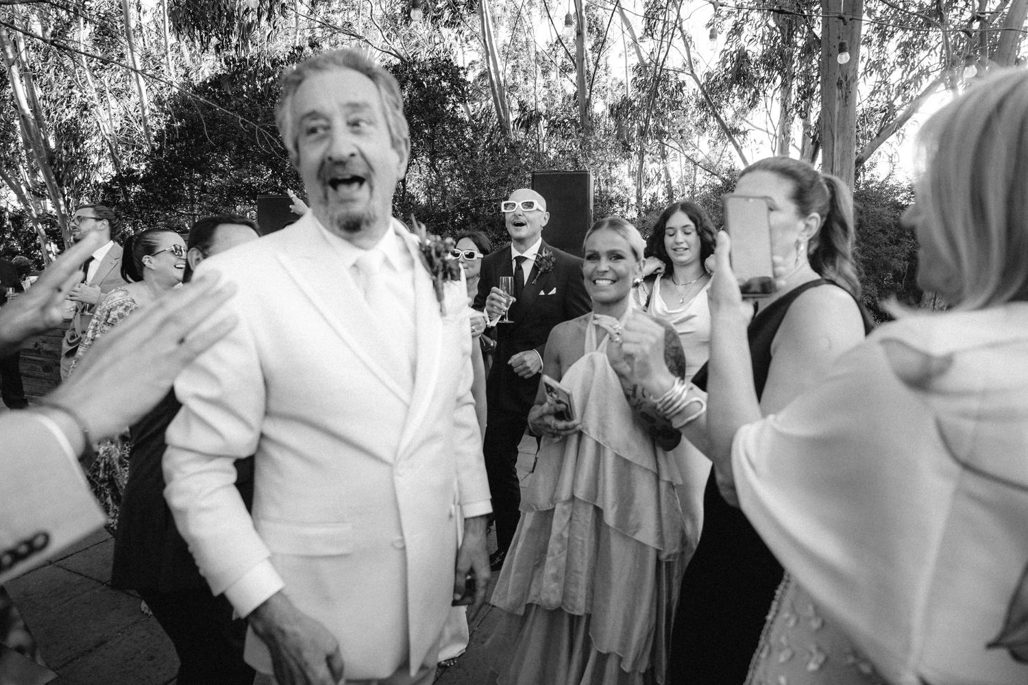 Black and white candid shots of wedding guests dancing and enjoying the celebration.