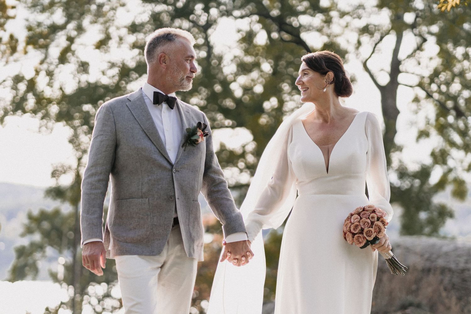 Wedding couple and attendants walking together in formal attire outdoors.