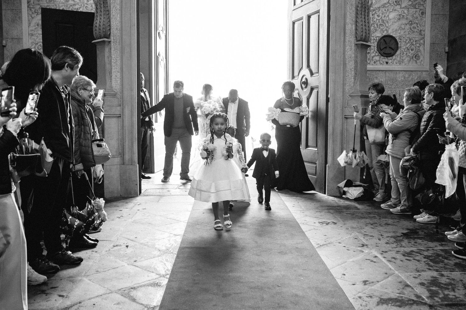 Wedding guests line the stone corridors of an ornate church during a ceremony.