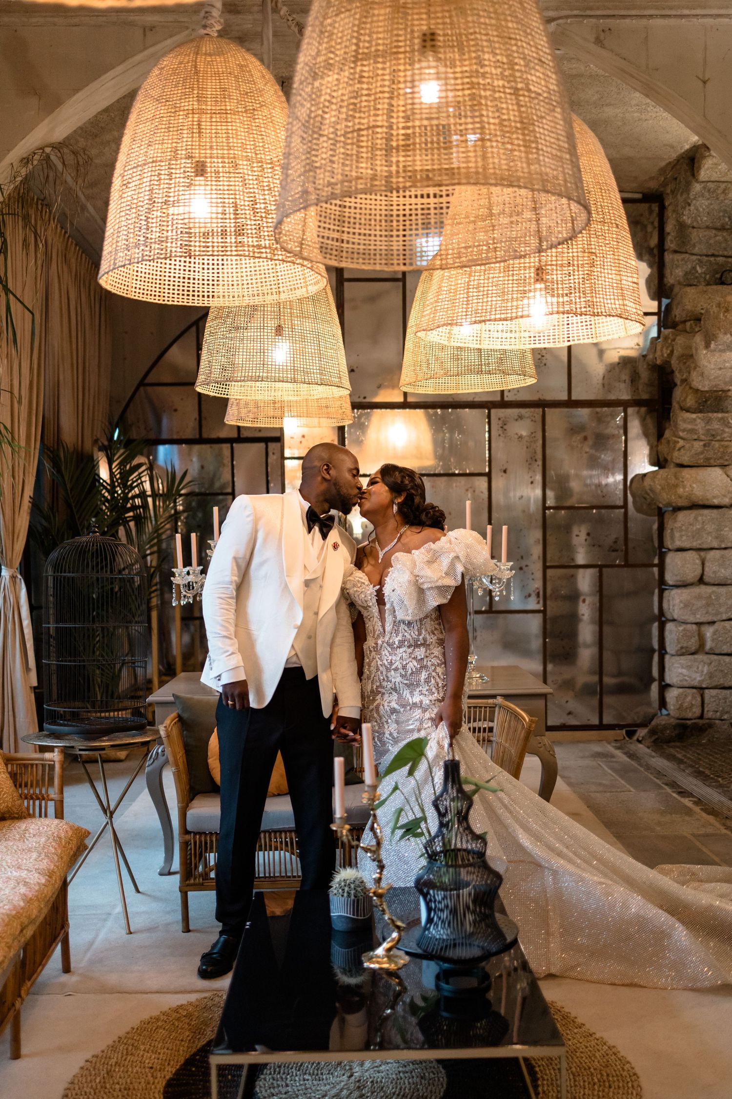 A romantic moment under woven pendant lights in an elegant stone-walled venue.