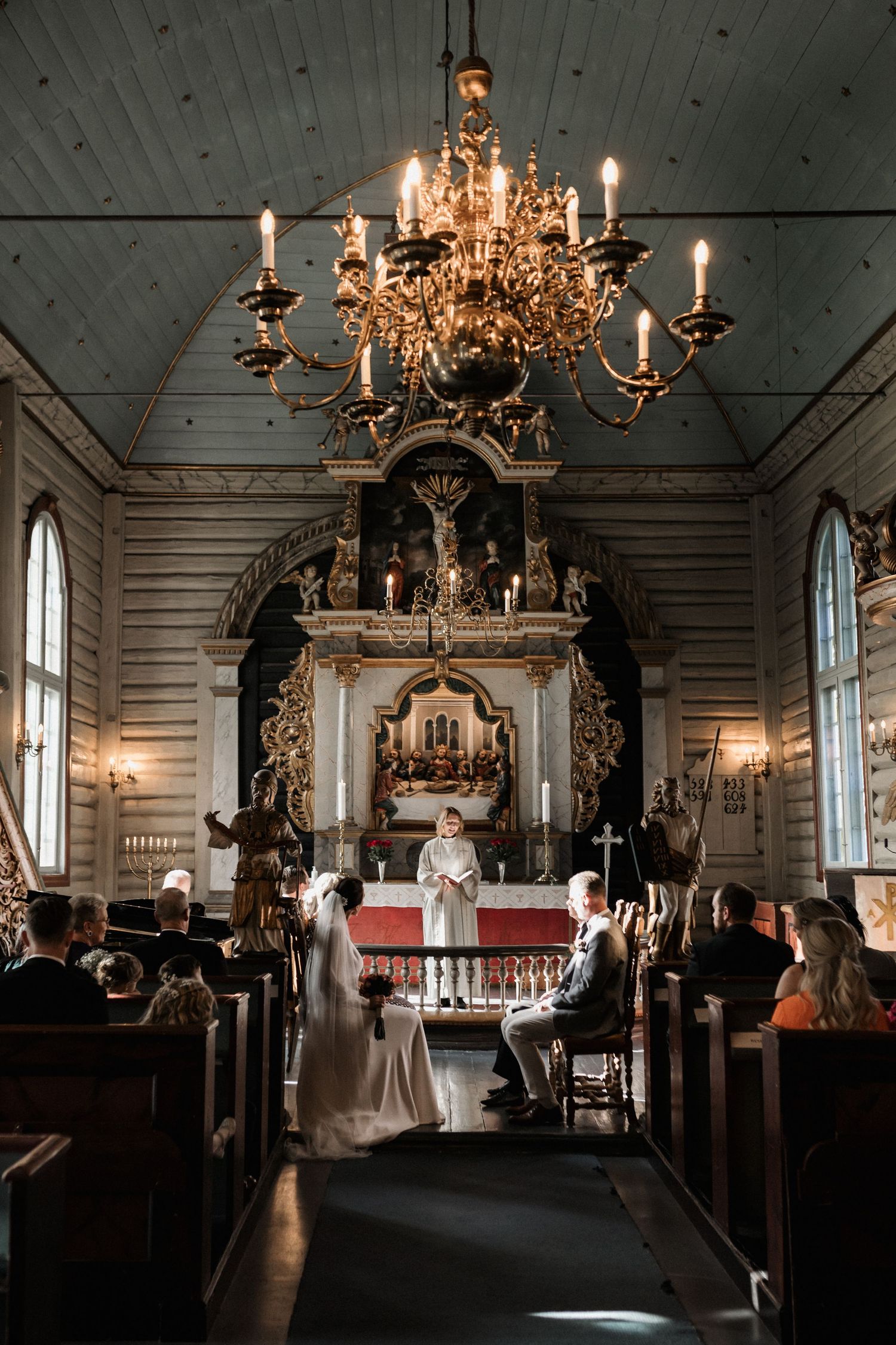 An elegant church interior with ornate chandeliers and wooden pews set up for a wedding ceremony.