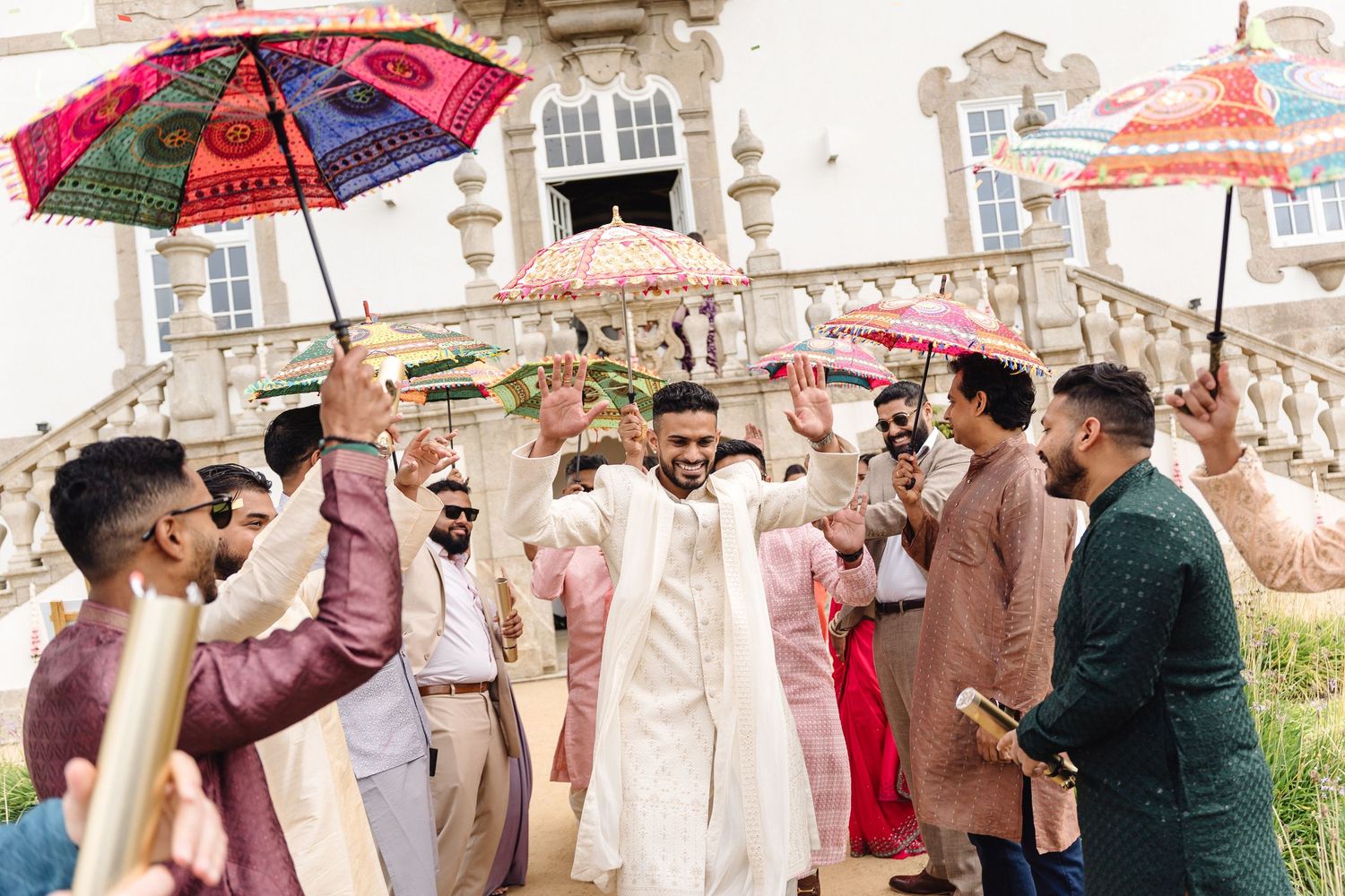 Colorful decorative umbrellas being held up during an outdoor celebration at a historic building.