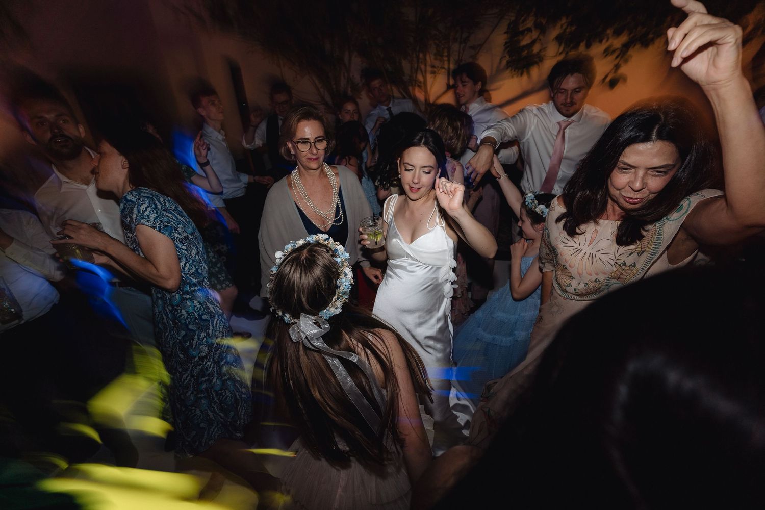 Energetic party scene with dancers moving under blue and yellow lighting effects.
