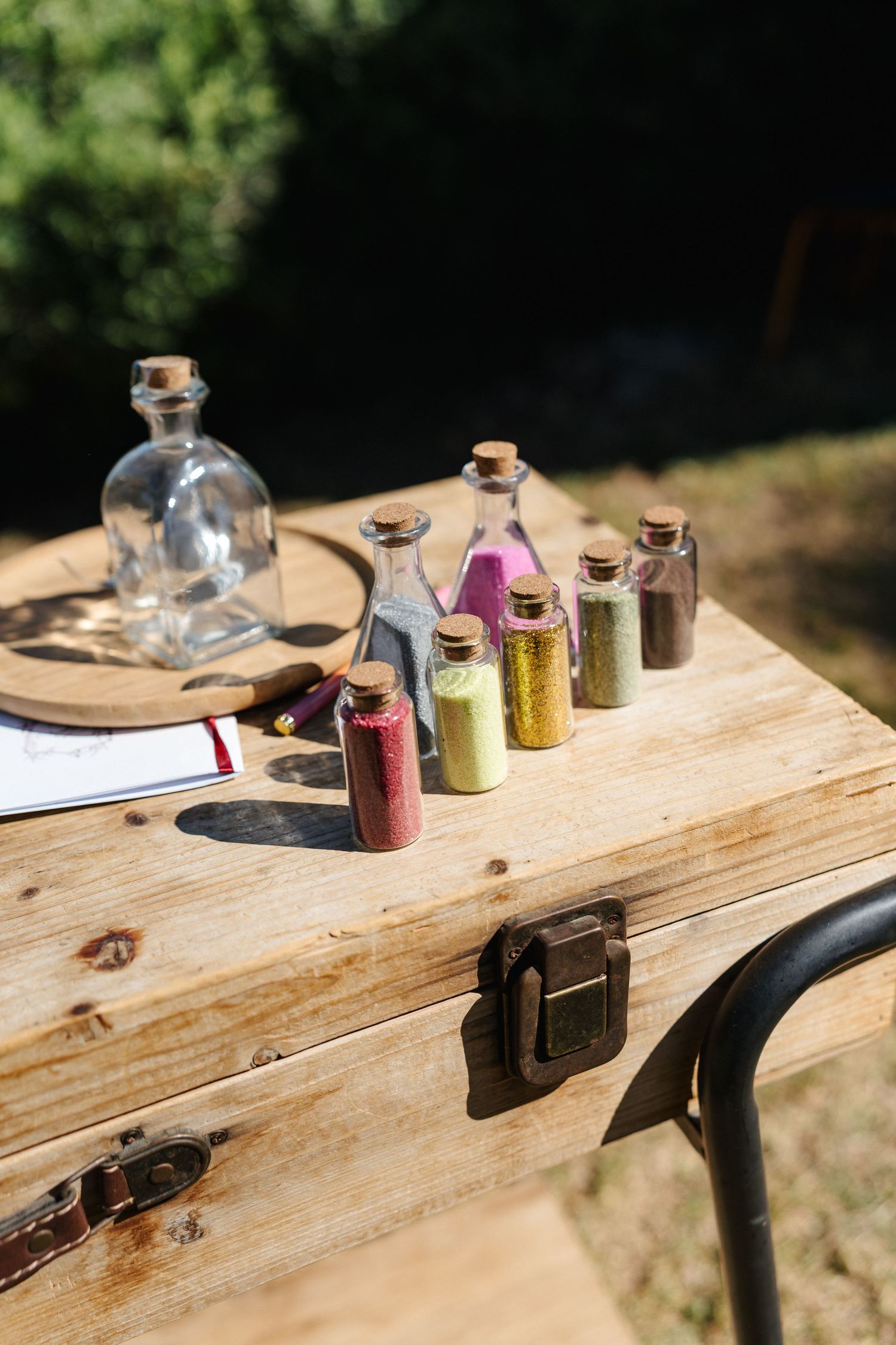 Decorative glass bottles with colorful contents arranged on rustic wooden table.