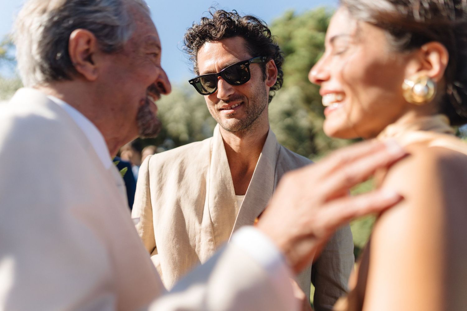 Guests sharing laughs and conversations during a sunny outdoor wedding celebration.