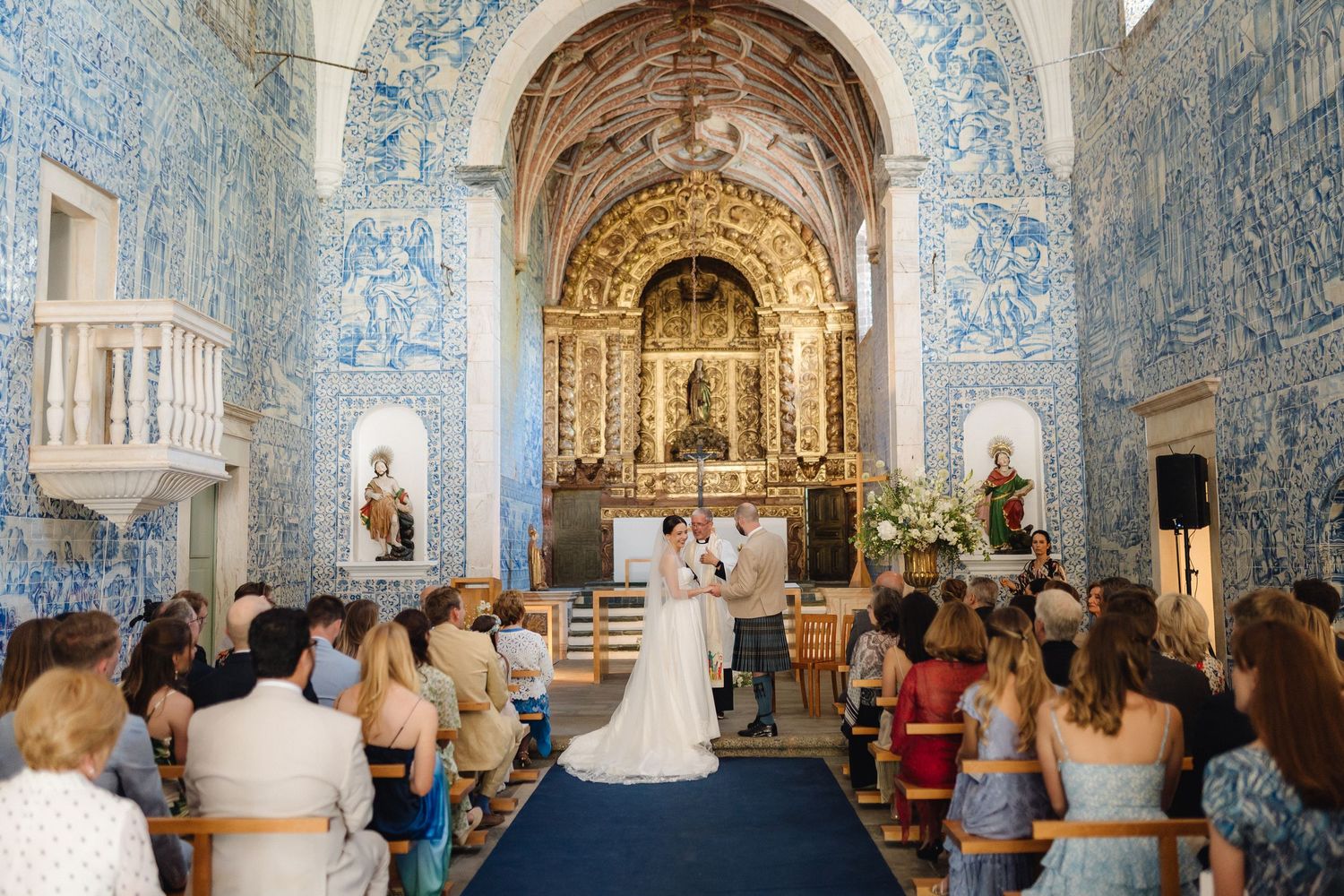 Panoramic view of Portuguese chapel interior with blue azulejo tiles and golden altar.