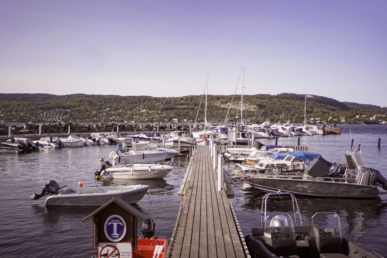 A series of panoramic marina views showing boats docked at wooden piers with mountains in the background.