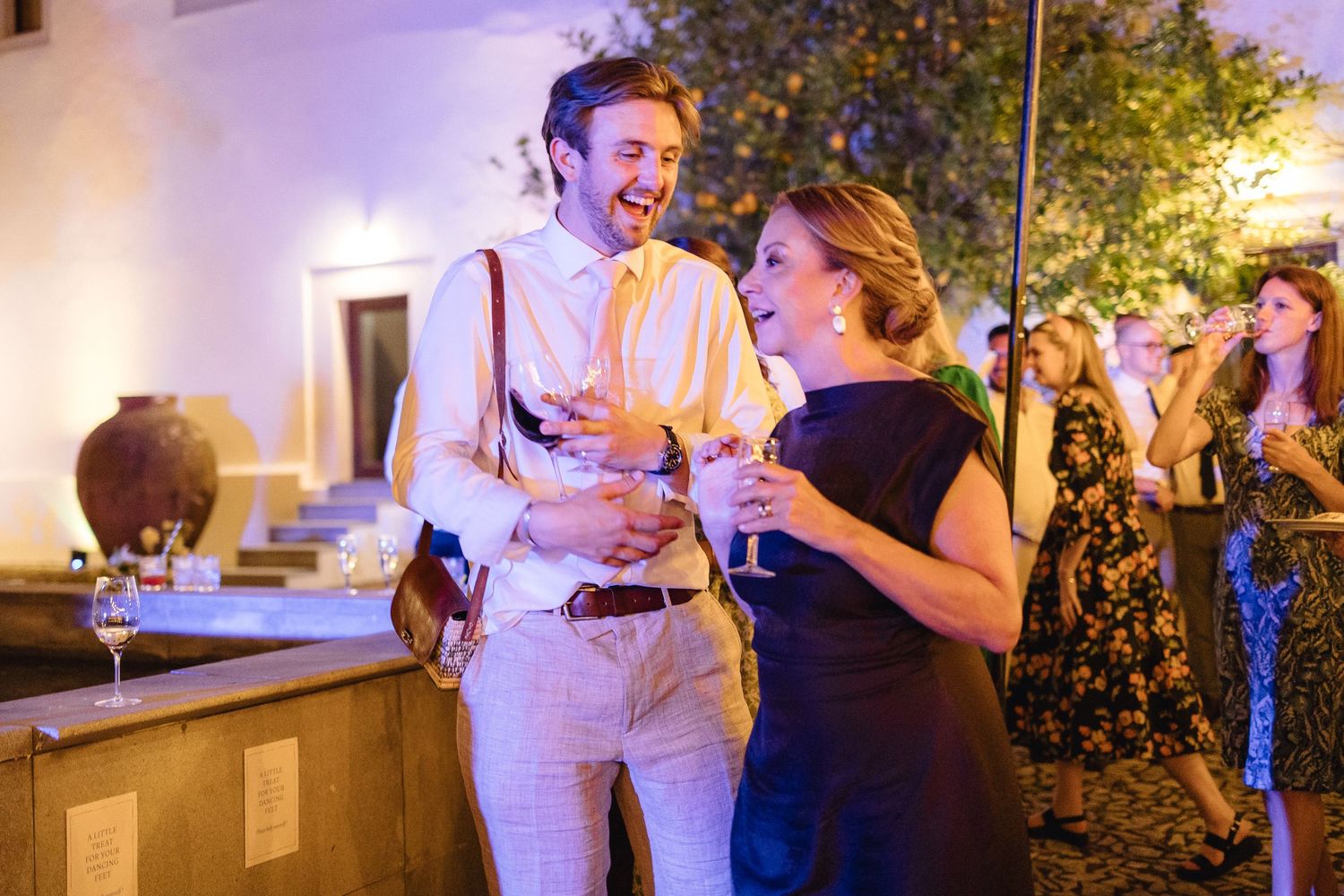 Couple enjoying drinks and conversation at an outdoor evening event.