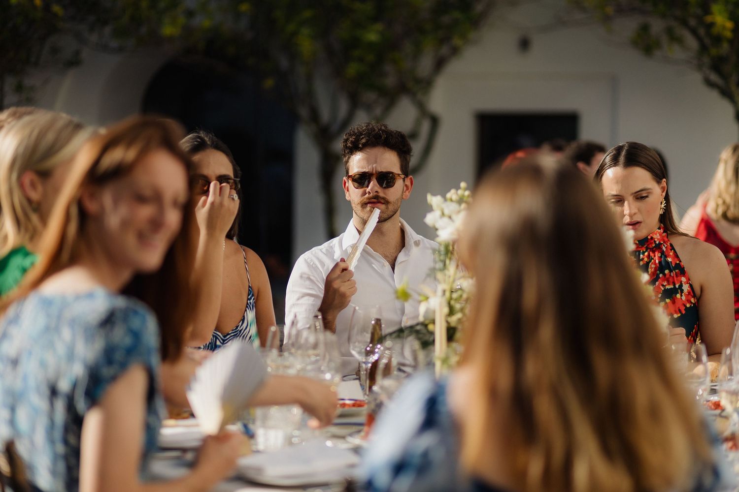 Guests enjoying a sunny outdoor wedding reception with tables and decorations.