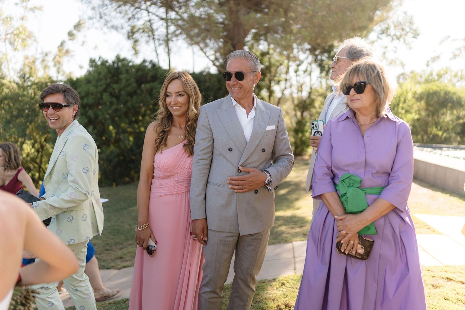 Wedding party members in pastel dresses mingling during an outdoor celebration.
