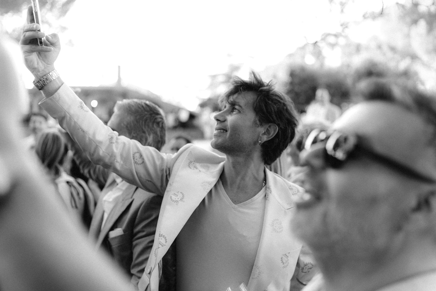 Black and white shot of wedding guests dancing with hands raised in celebration.
