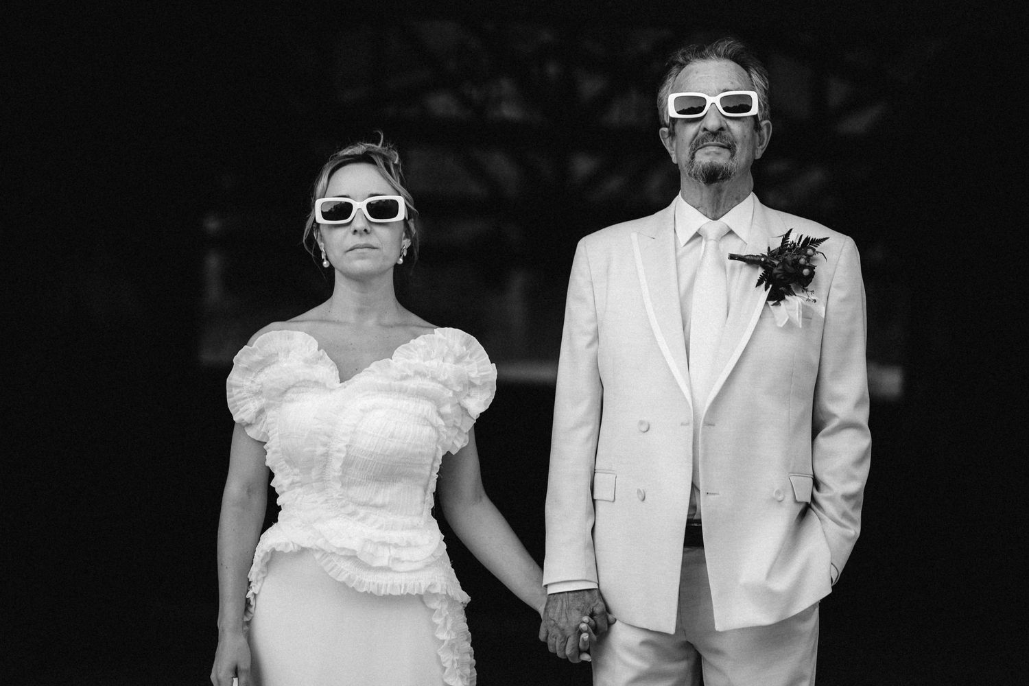 A couple wearing sunglasses poses in black and white photography.