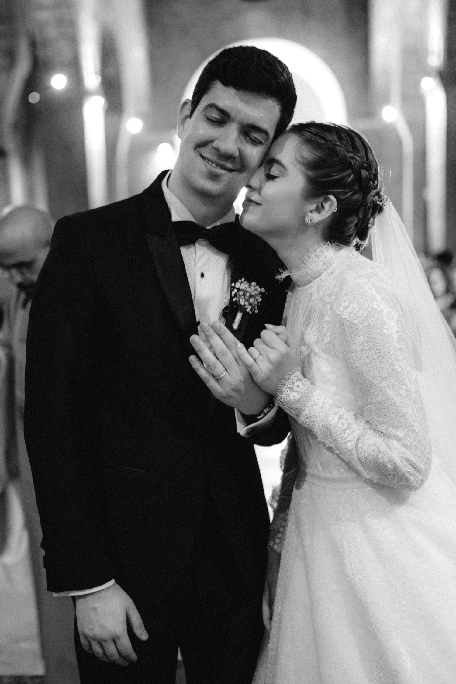 Bride and groom share tender moment during wedding ceremony in black and white portrait.