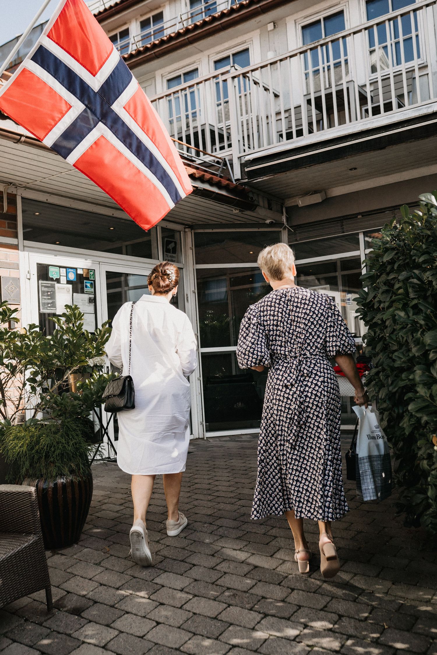 Wedding guests walking with Norwegian flags outside a building during a celebration.
