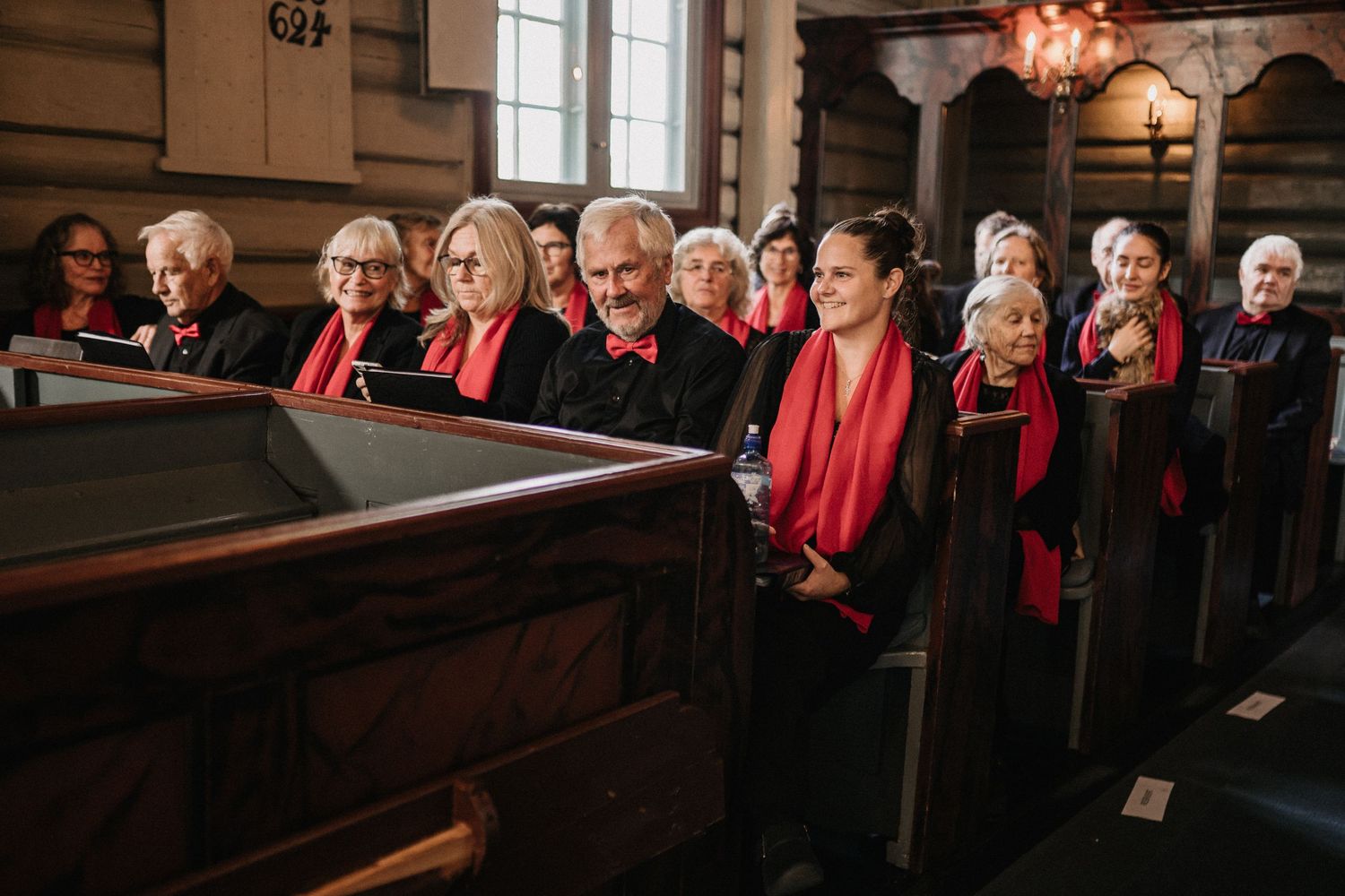 Church pews filled with choir members in red robes during a ceremony.