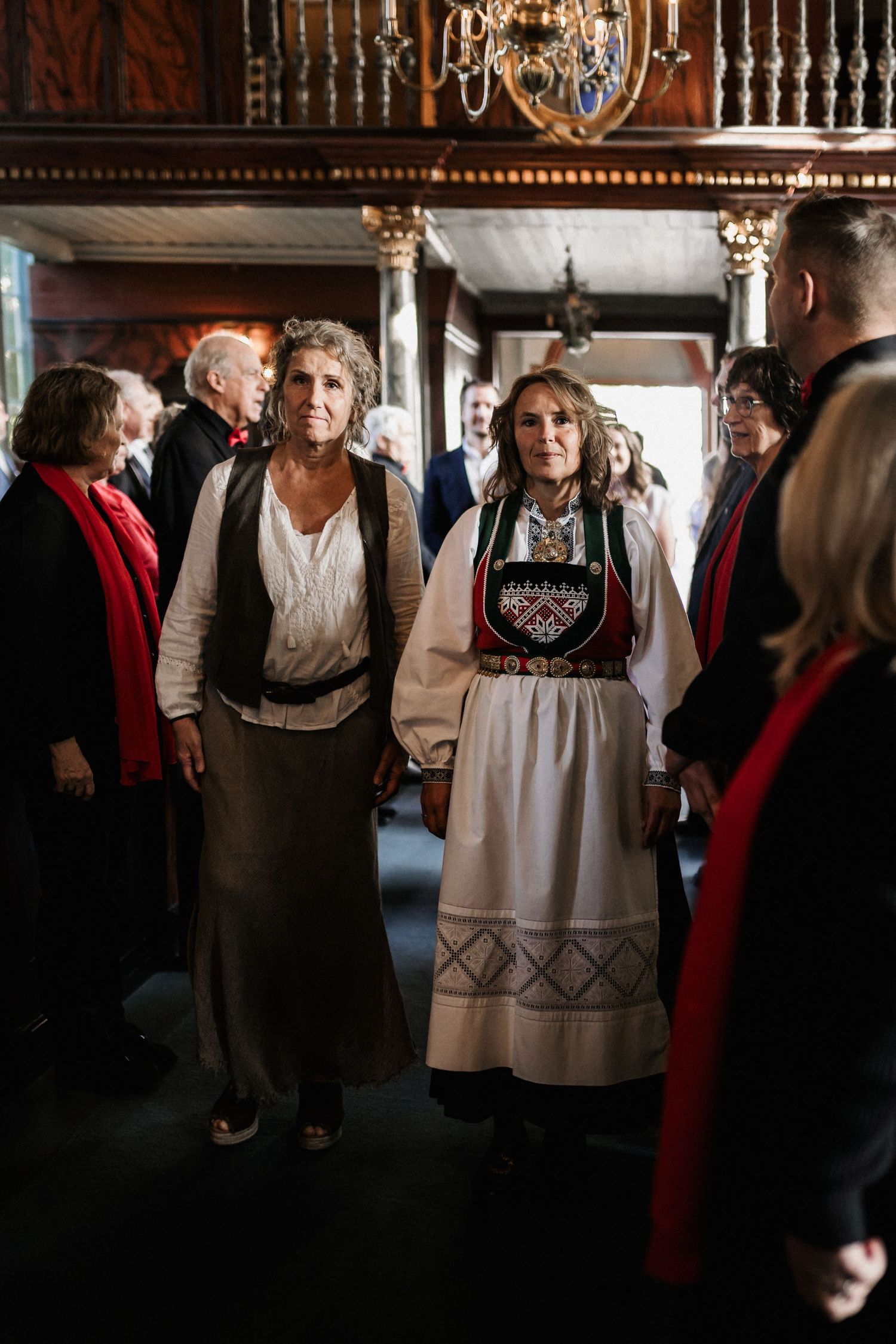 People gathered in traditional Norwegian folk costumes inside an ornate church interior.