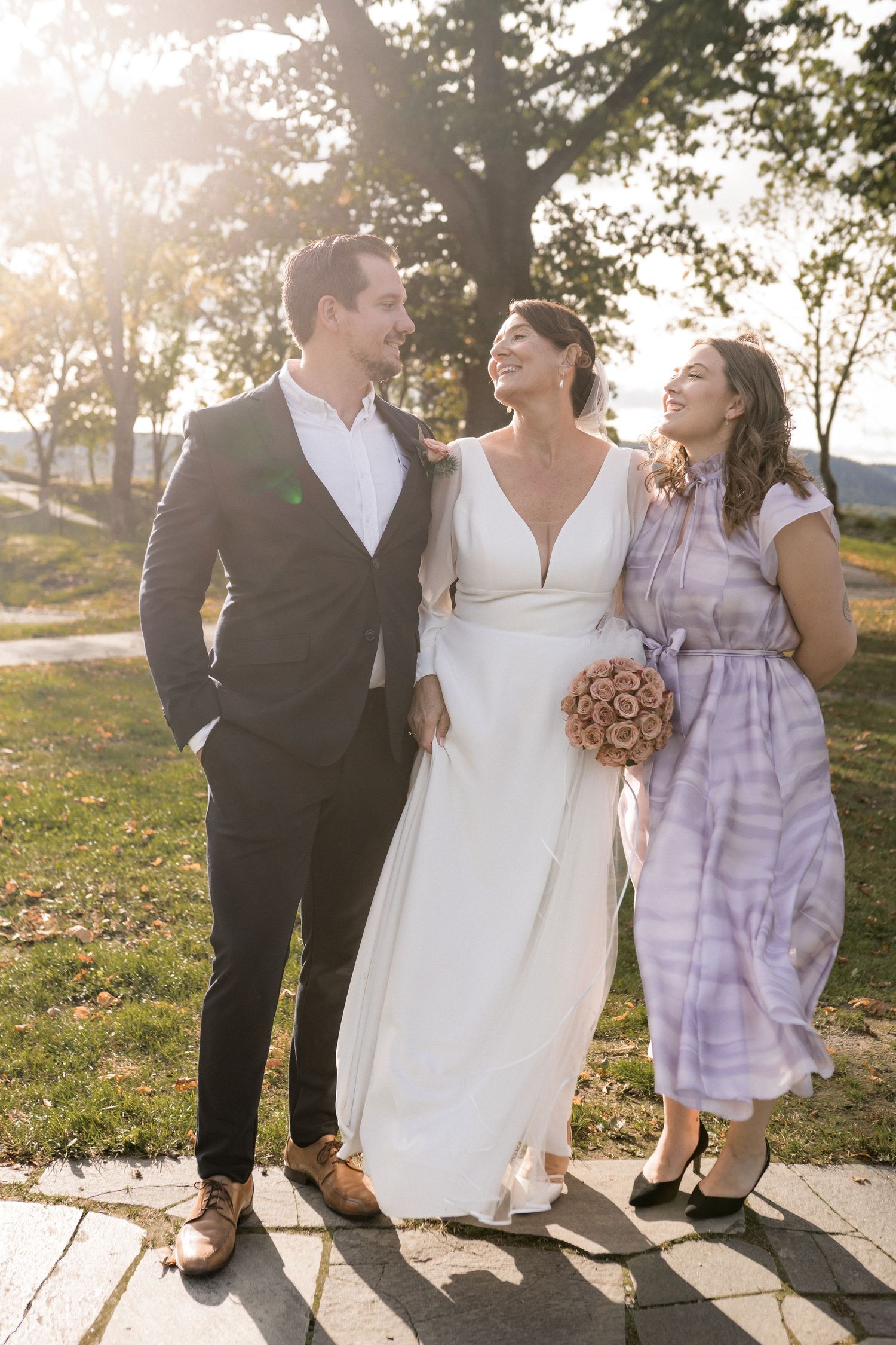 Wedding party poses together on a sunlit pathway during golden hour.