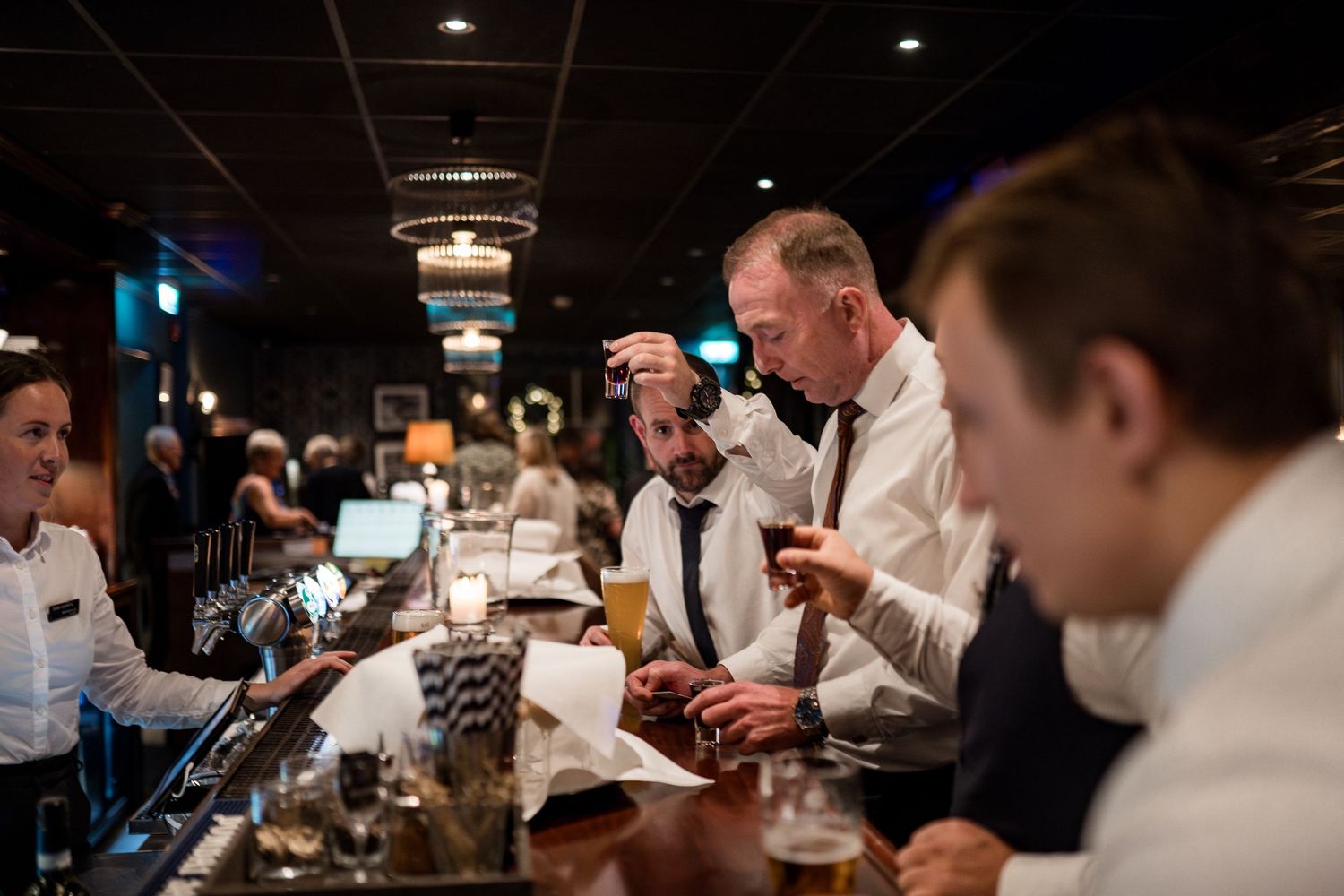 Dark atmospheric restaurant dining room with guests seated at tables during evening service.