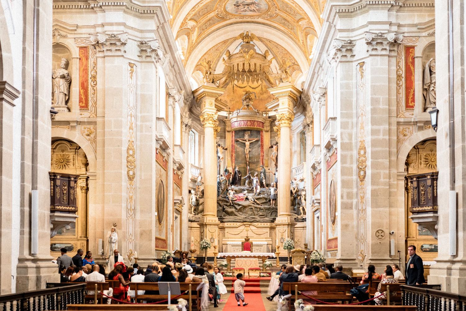 Ornate cathedral interior with baroque architecture and gilded details in panoramic view.