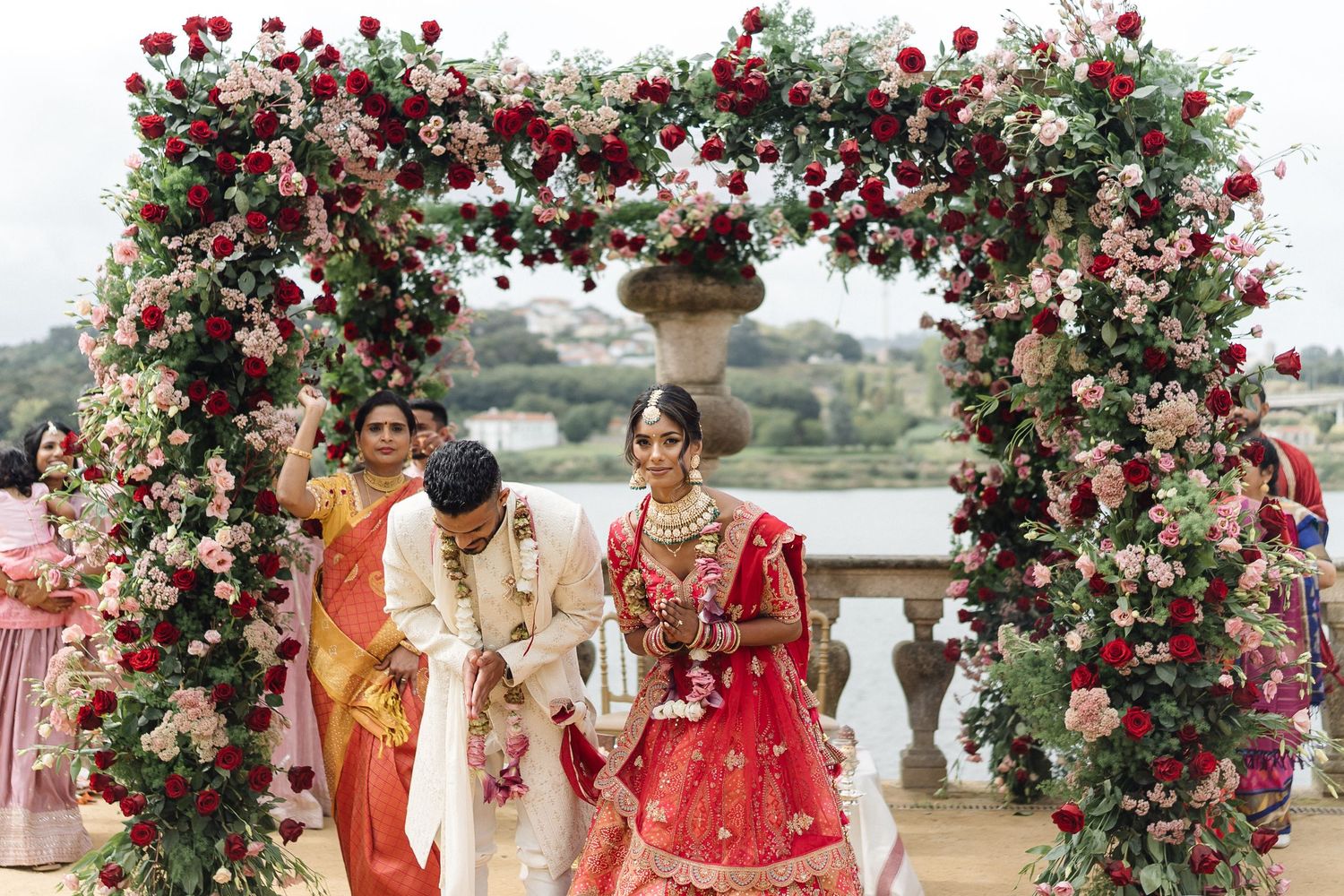 Beautiful floral arch with red roses decorating outdoor wedding ceremony space.