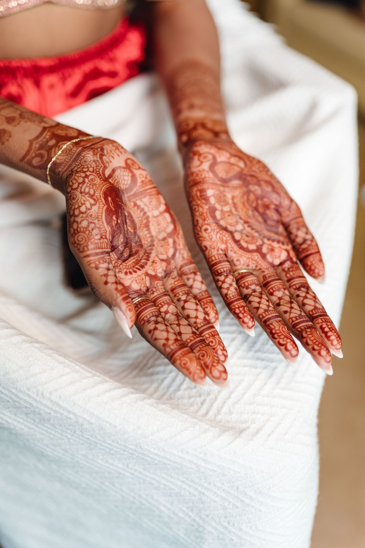Detailed henna mehndi designs on hands displayed against white fabric.