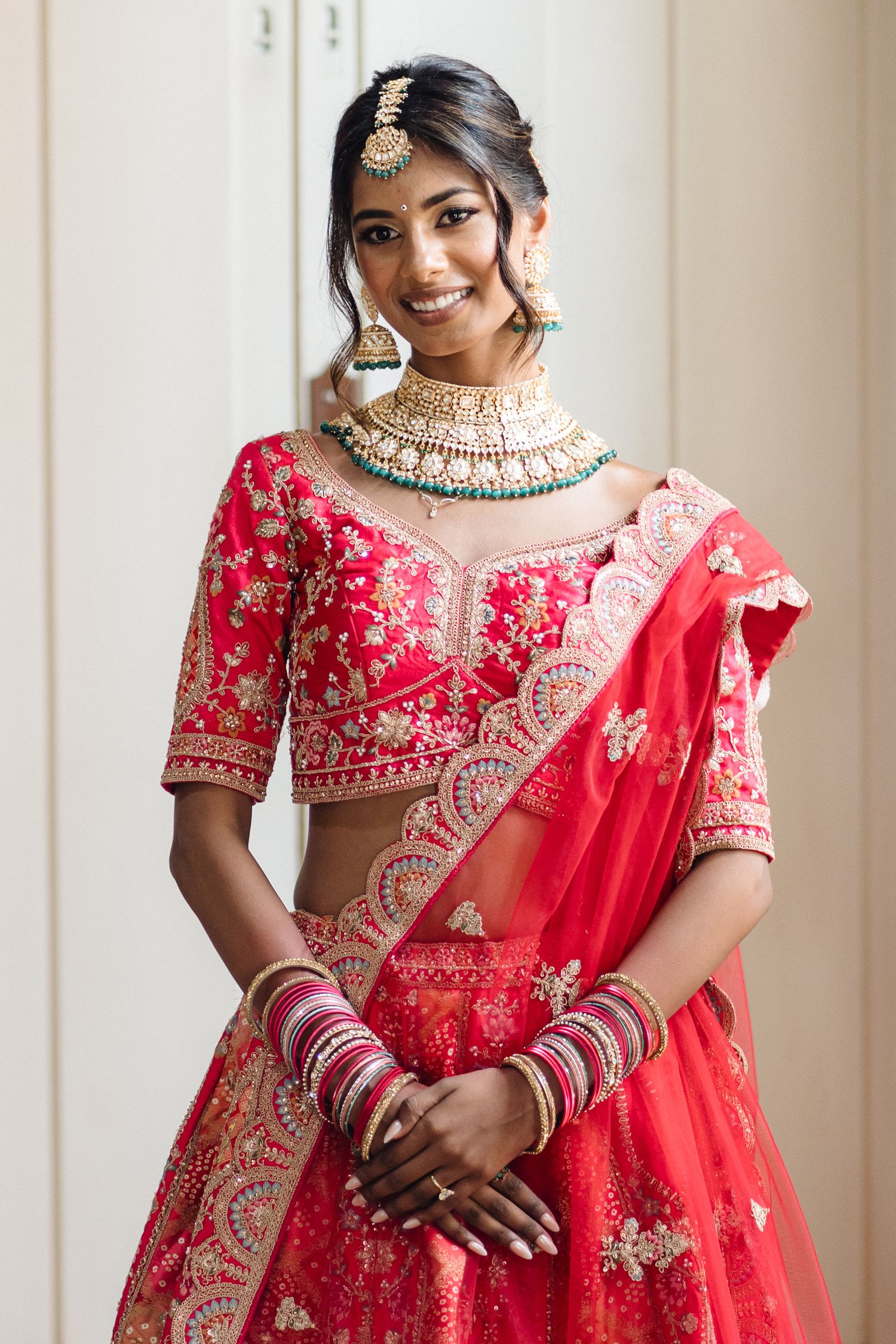 Traditional bridal wear featuring red lehenga with intricate embroidery and jewelry.