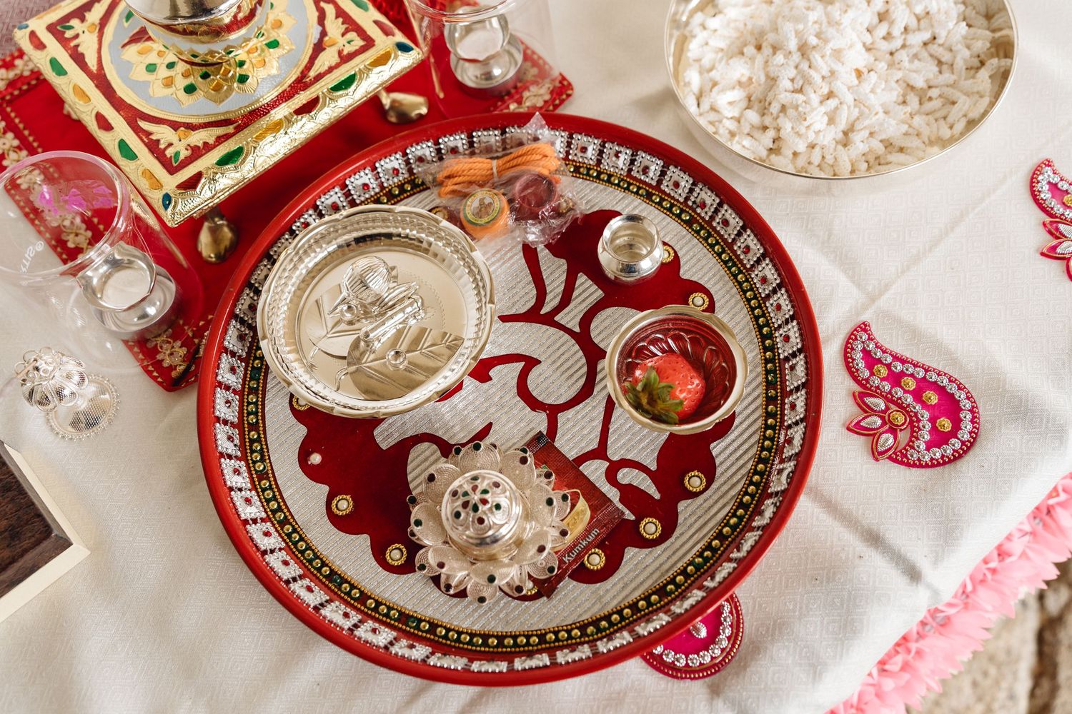 Traditional Indian wedding plates with ornate red and gold designs on white tablecloth.