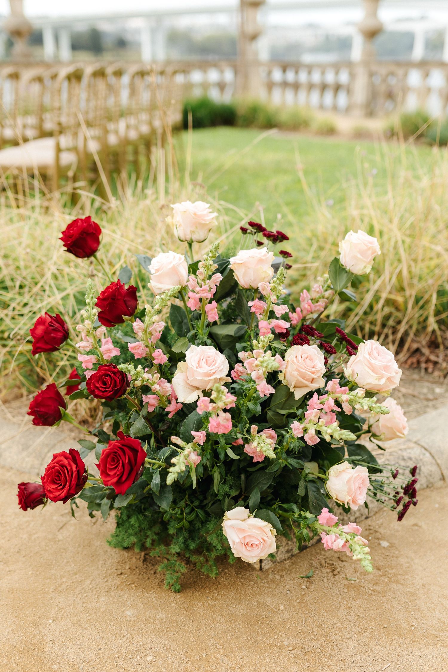 Beautiful floral arrangement with red and pink roses decorating an outdoor space.