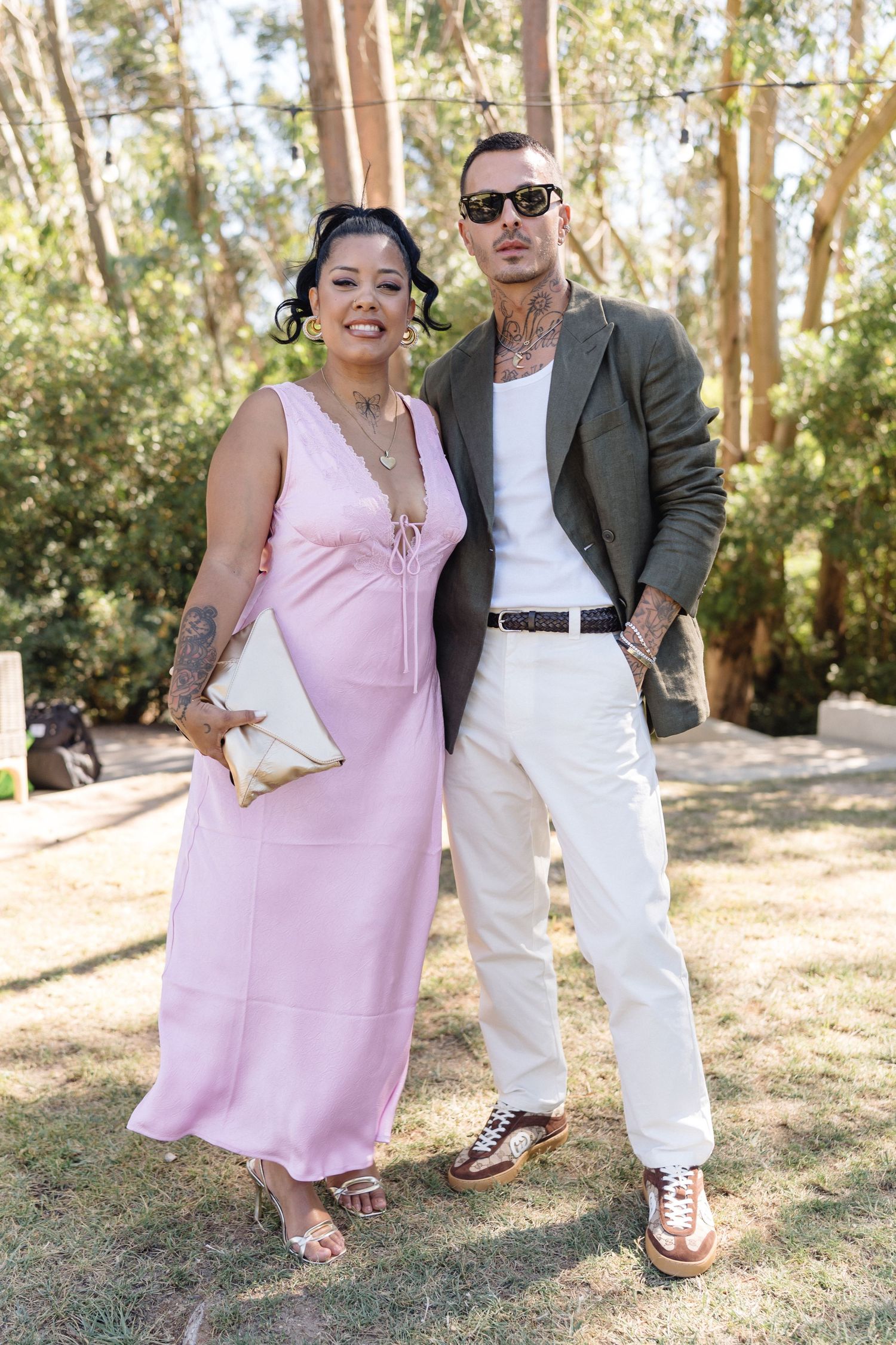 Couple in coordinated formal wear poses together at outdoor event.