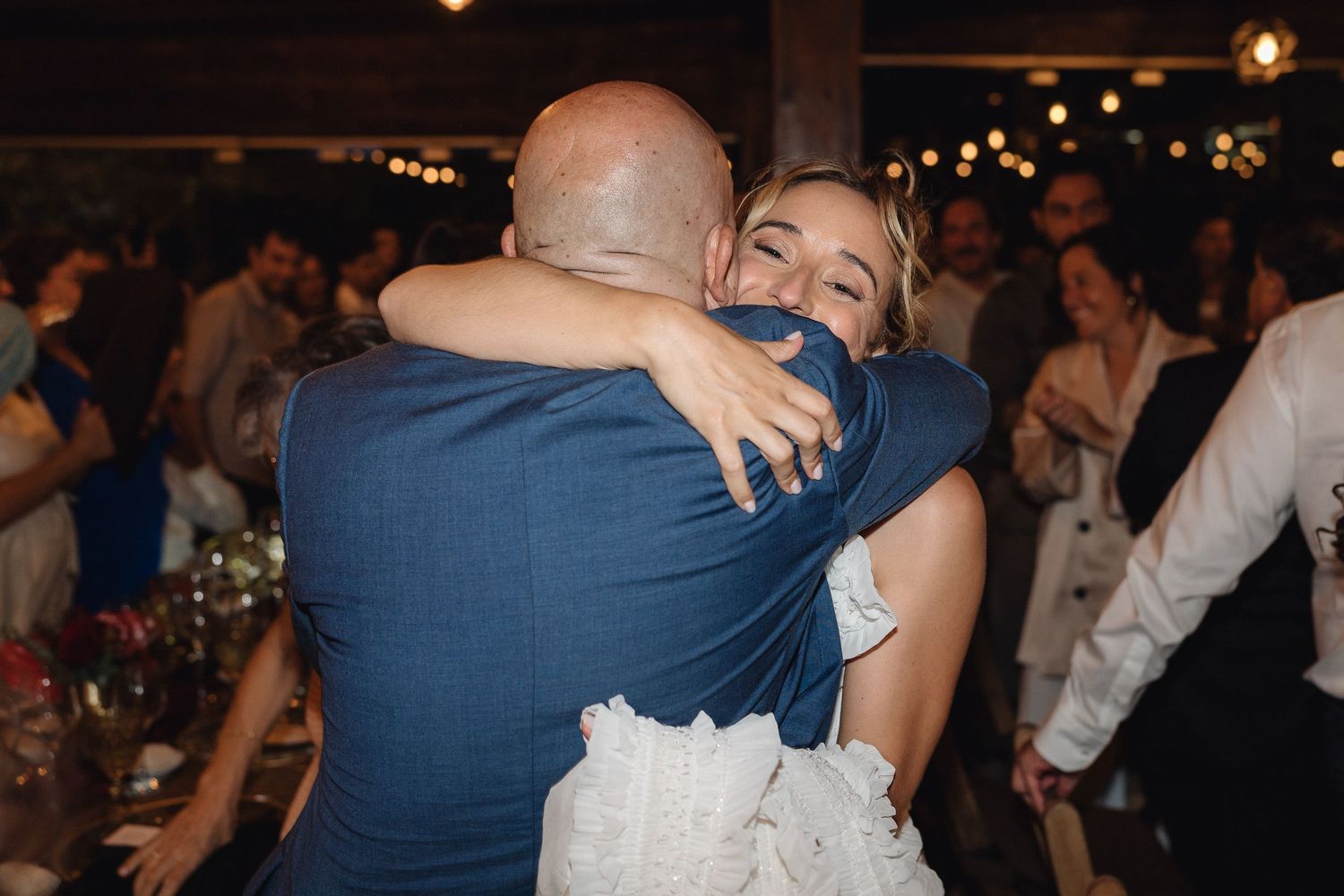Wedding celebration with guests sharing emotional embraces on the dance floor.