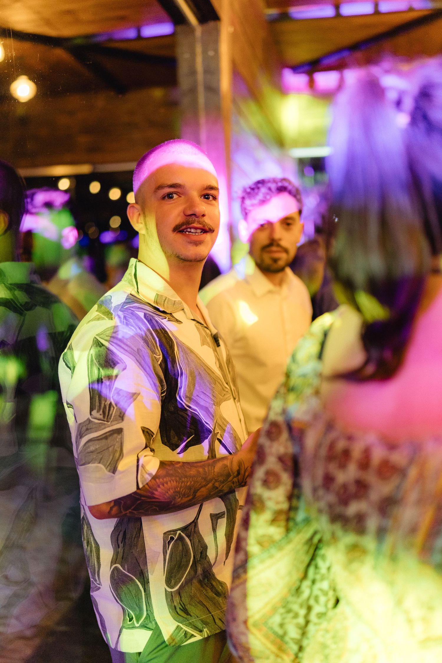 Wedding reception with colorful lighting effects creating a vibrant dance floor atmosphere.