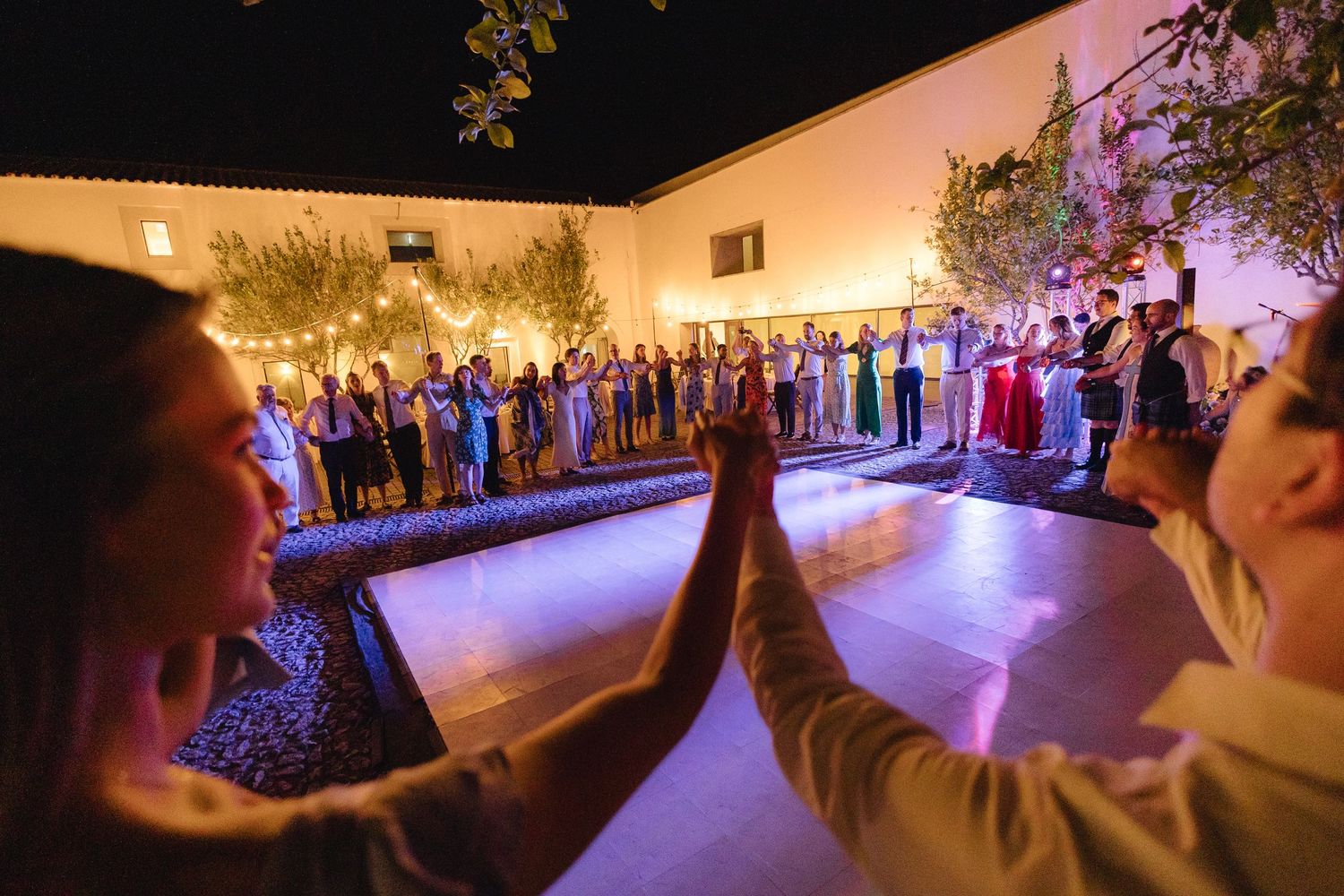 Wide shot of a wedding reception venue with warm lighting and guests on the dance floor.