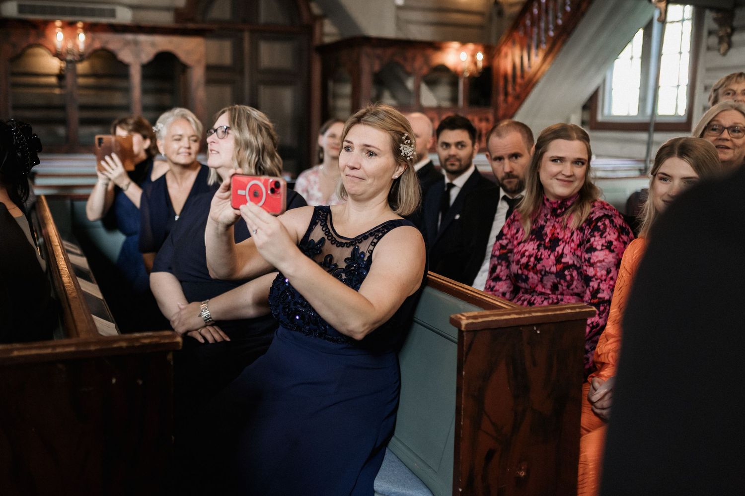 Wedding guests dancing and celebrating together on a dimly lit dance floor at an indoor reception venue.