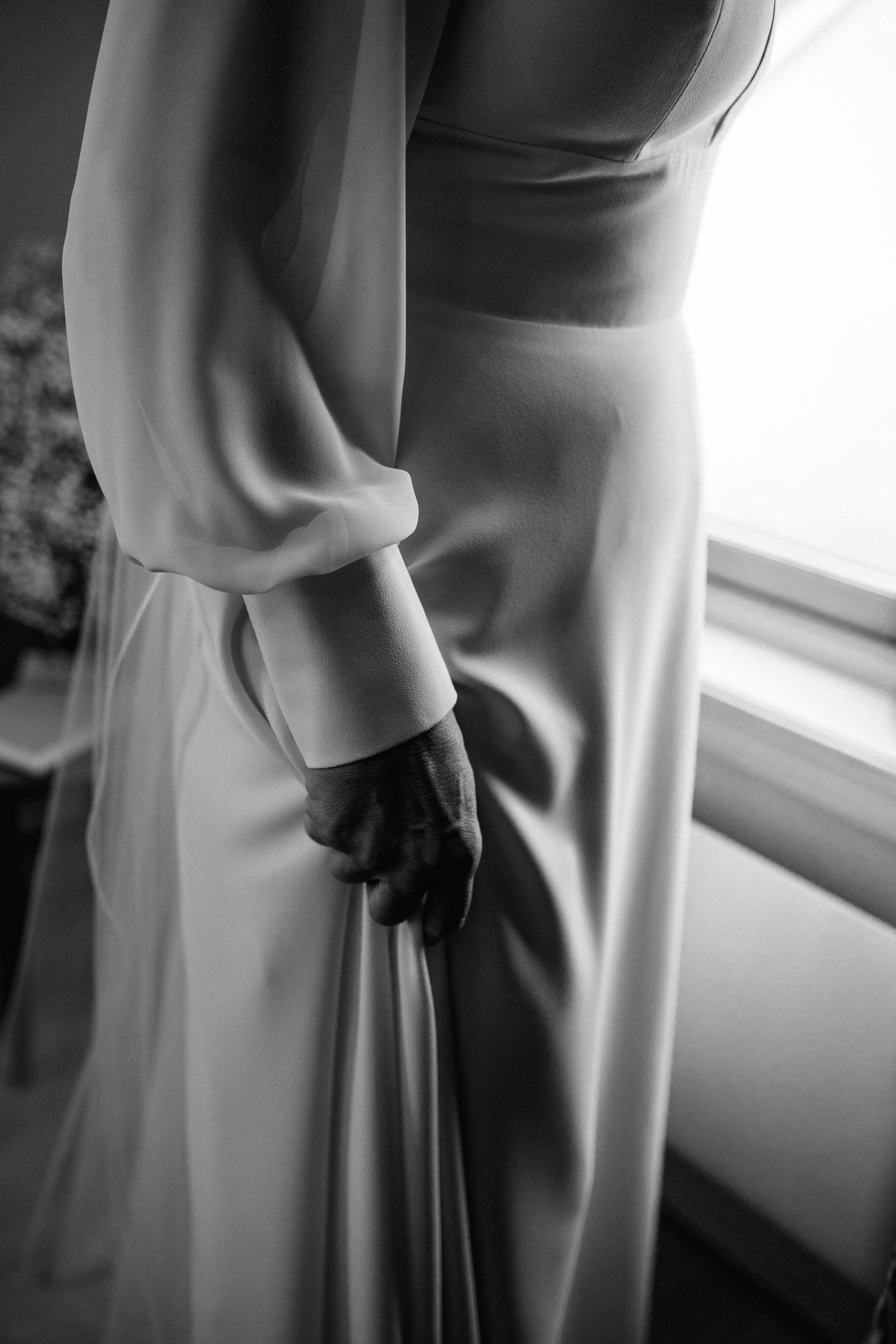 Black and white artistic photos showing the elegant draping and movement of a wedding dress near a window.