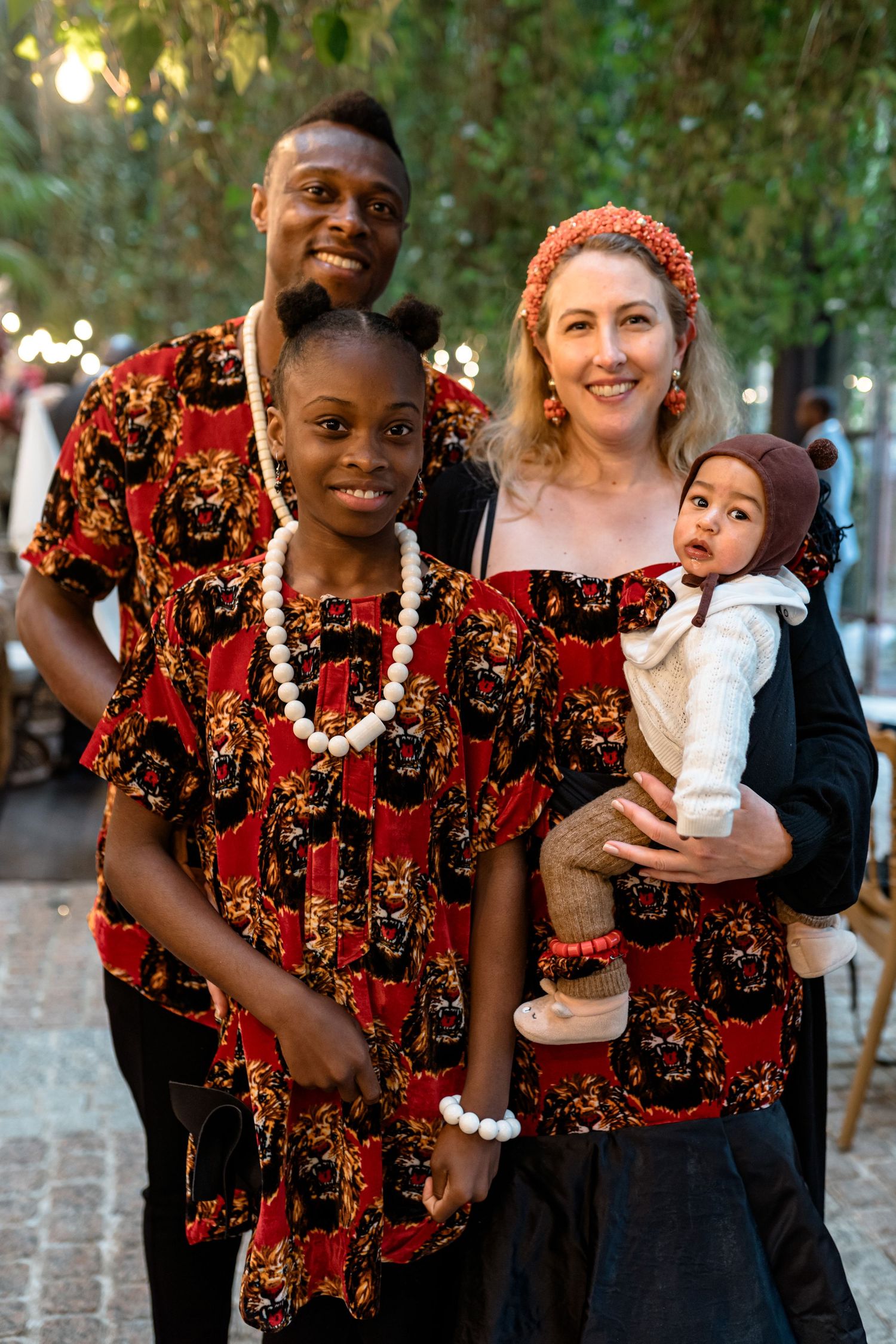 Children in vibrant red and black patterned outfits enjoying a celebration outdoors.