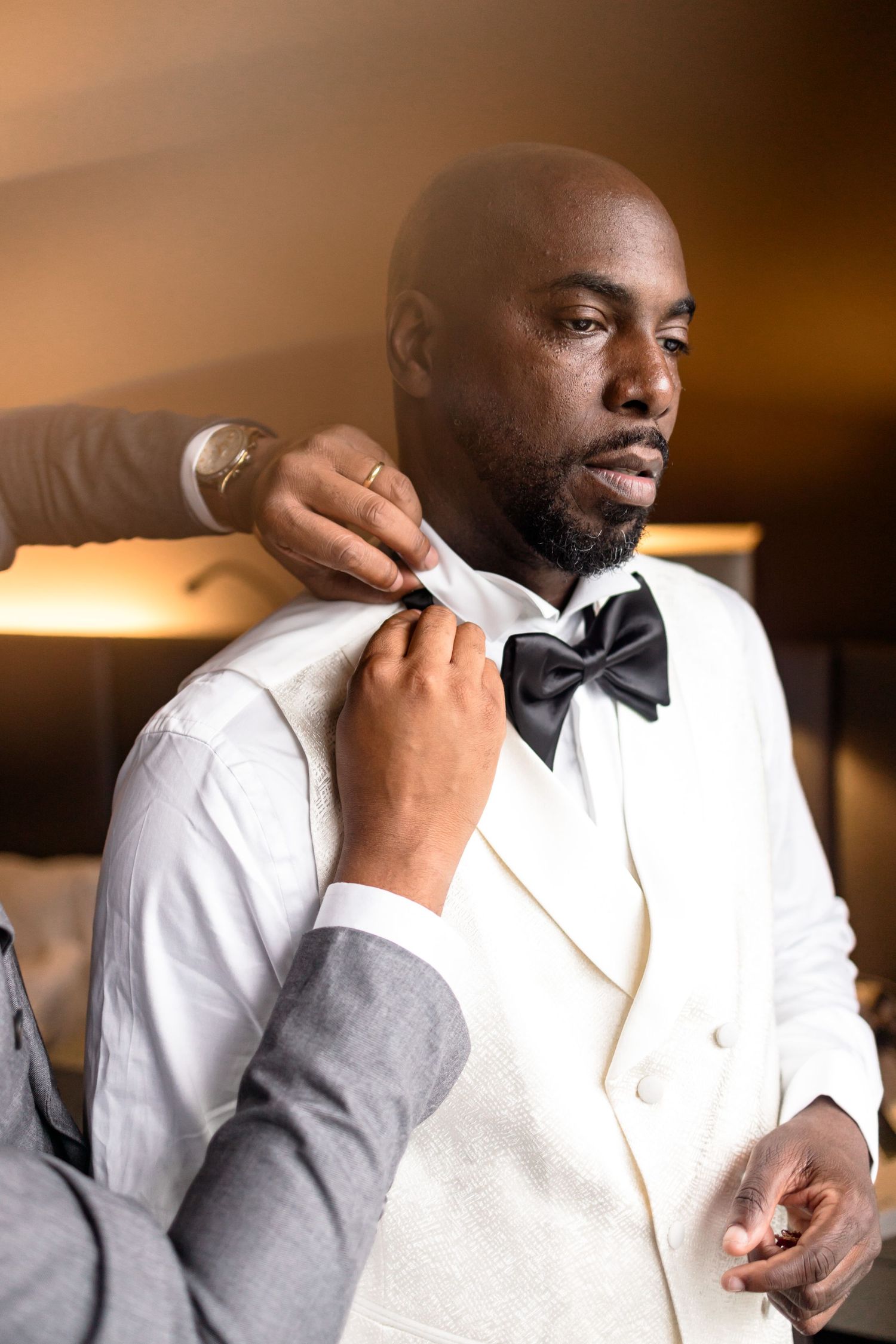 Close-up details of white tuxedo and bowtie adjustments.