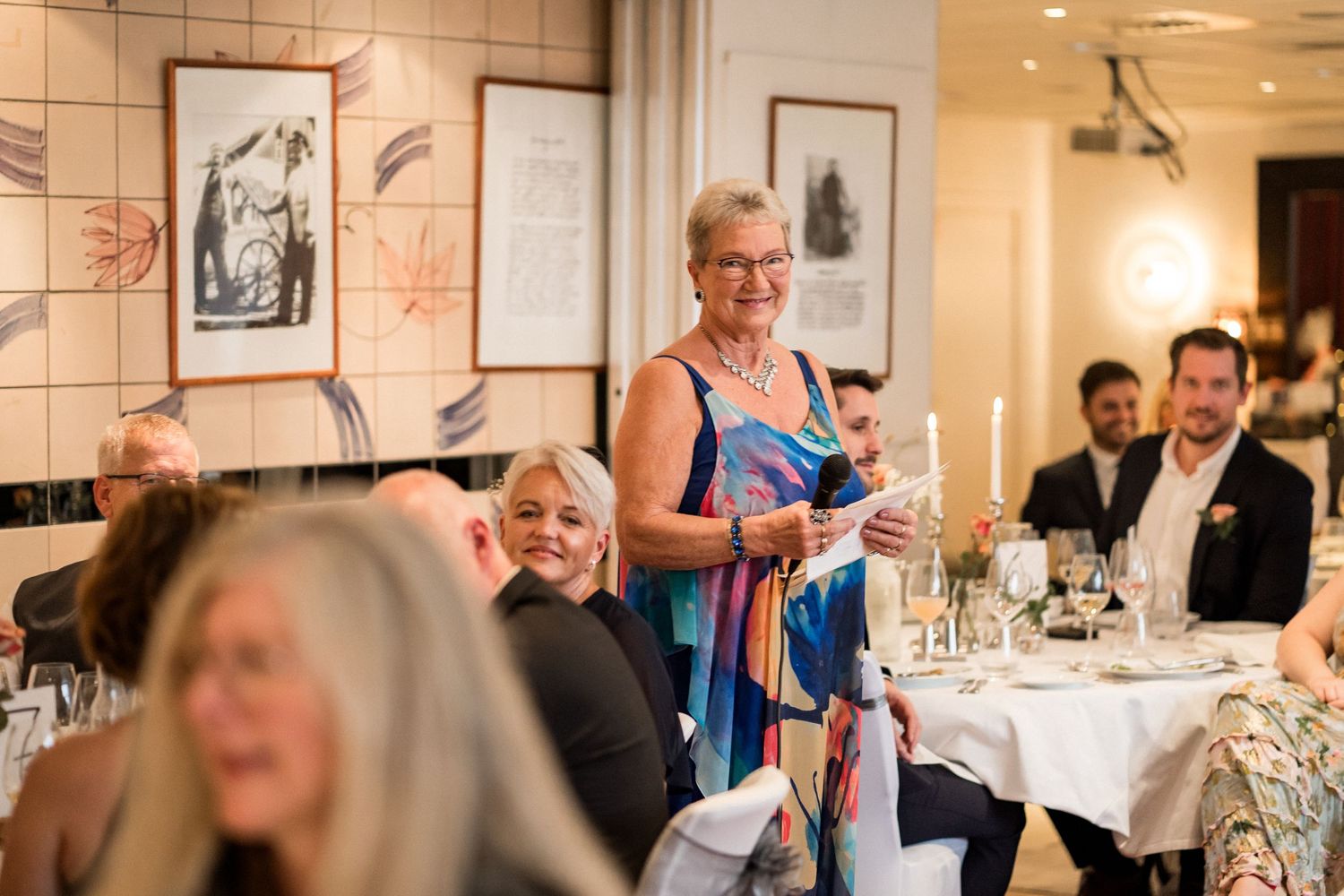 Guests enjoy a formal dinner celebration in an elegant restaurant setting with white tablecloths.