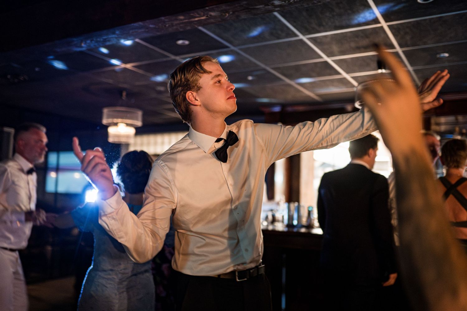 Wedding reception dance floor moments captured under dramatic lighting.