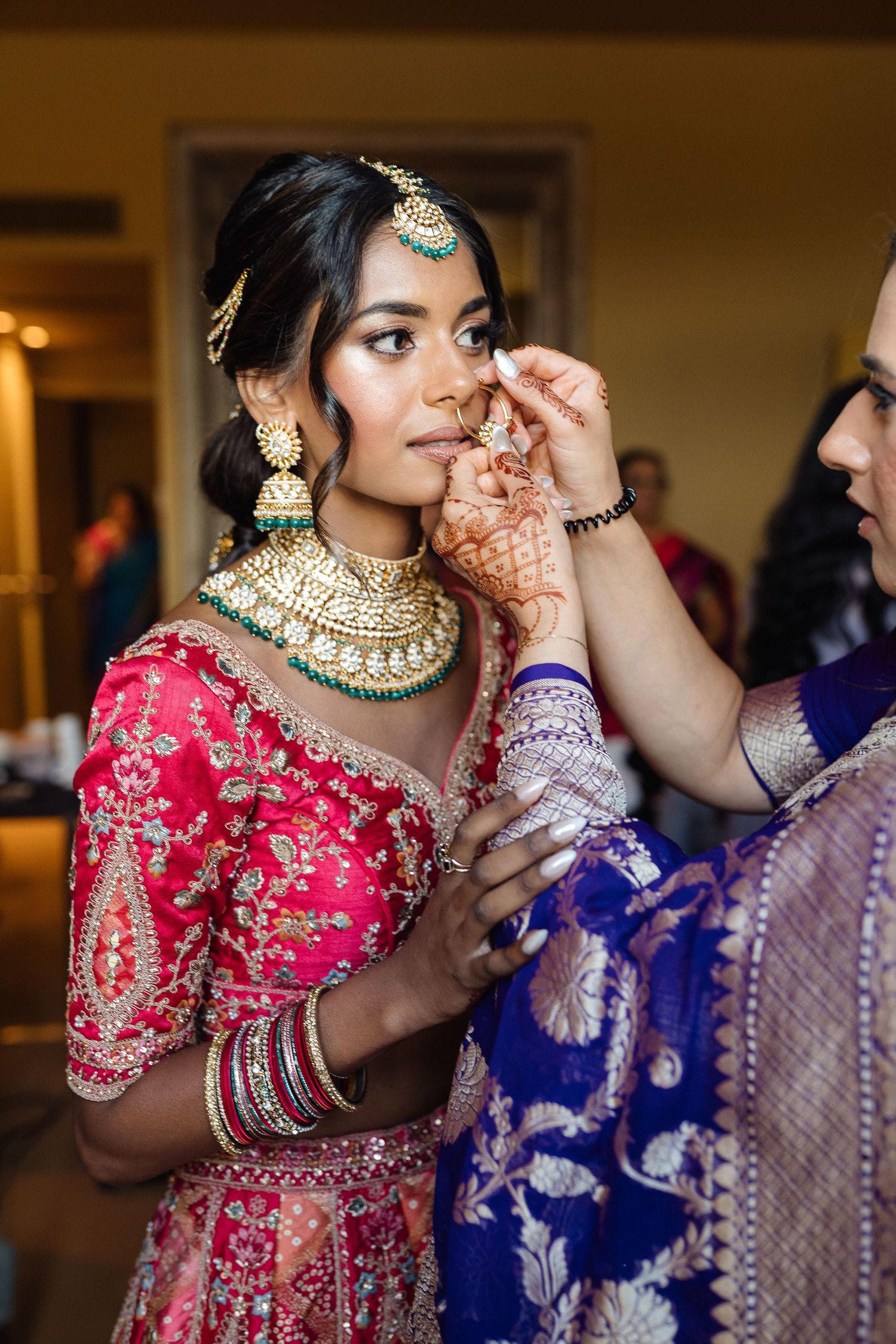 Traditional Indian bridal preparation showing ornate jewelry and red embroidered lehenga during getting ready moments.
